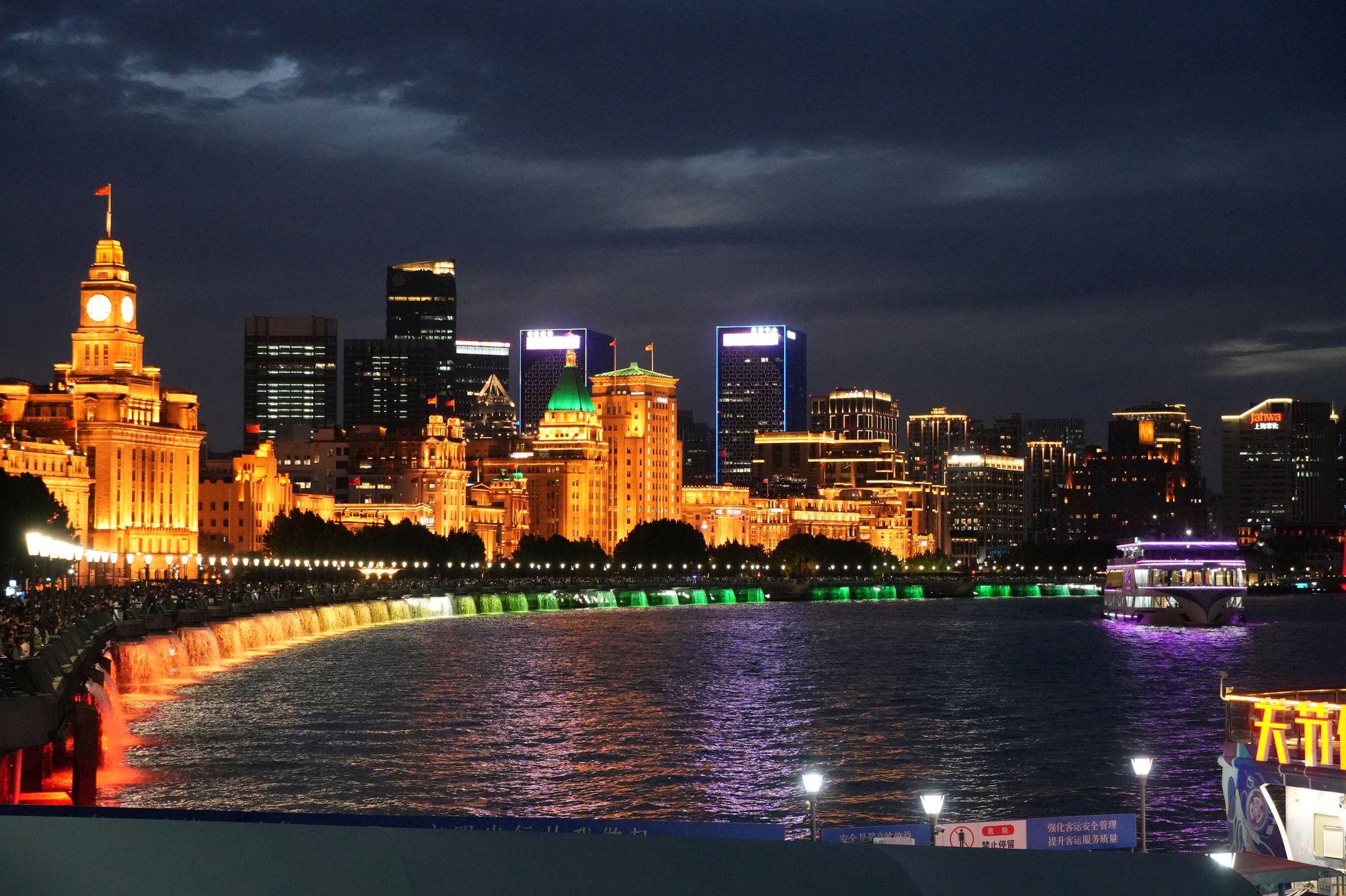 Waterfront skyline reflected in a river with boats at night, Shanghai