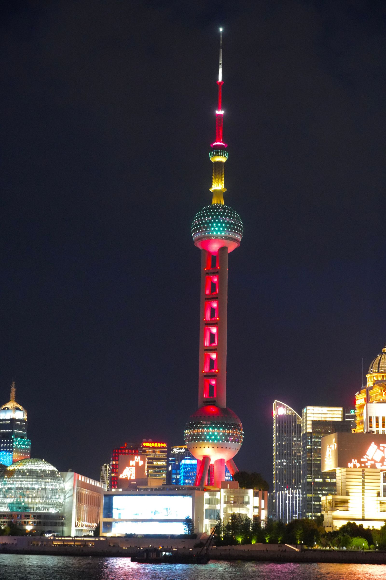 A colorful spherical tower above waterfront buildings at night, Shanghai