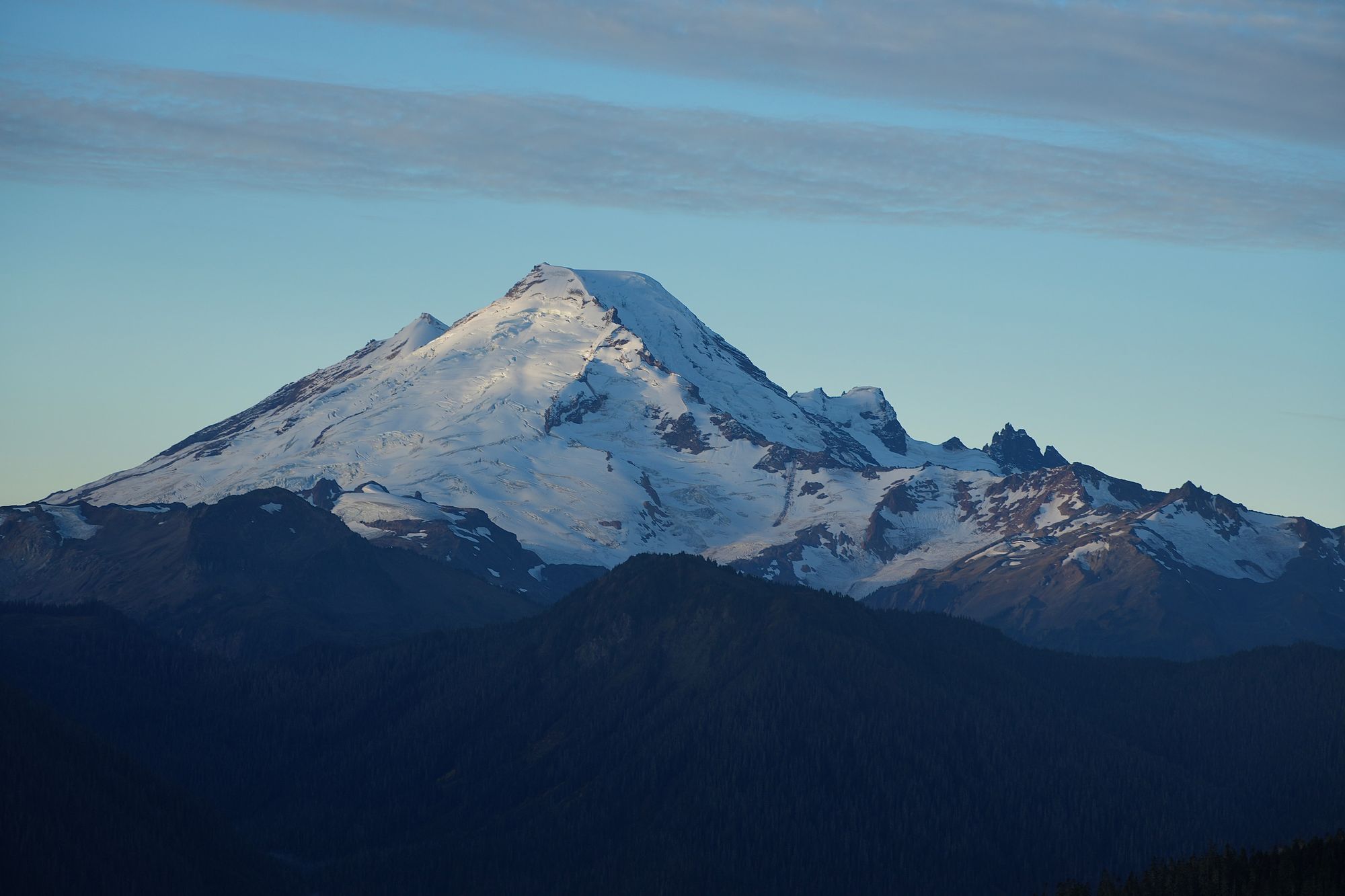 Snow-covered Mount Baker above dark forested ridges, Yellow Aster Butte