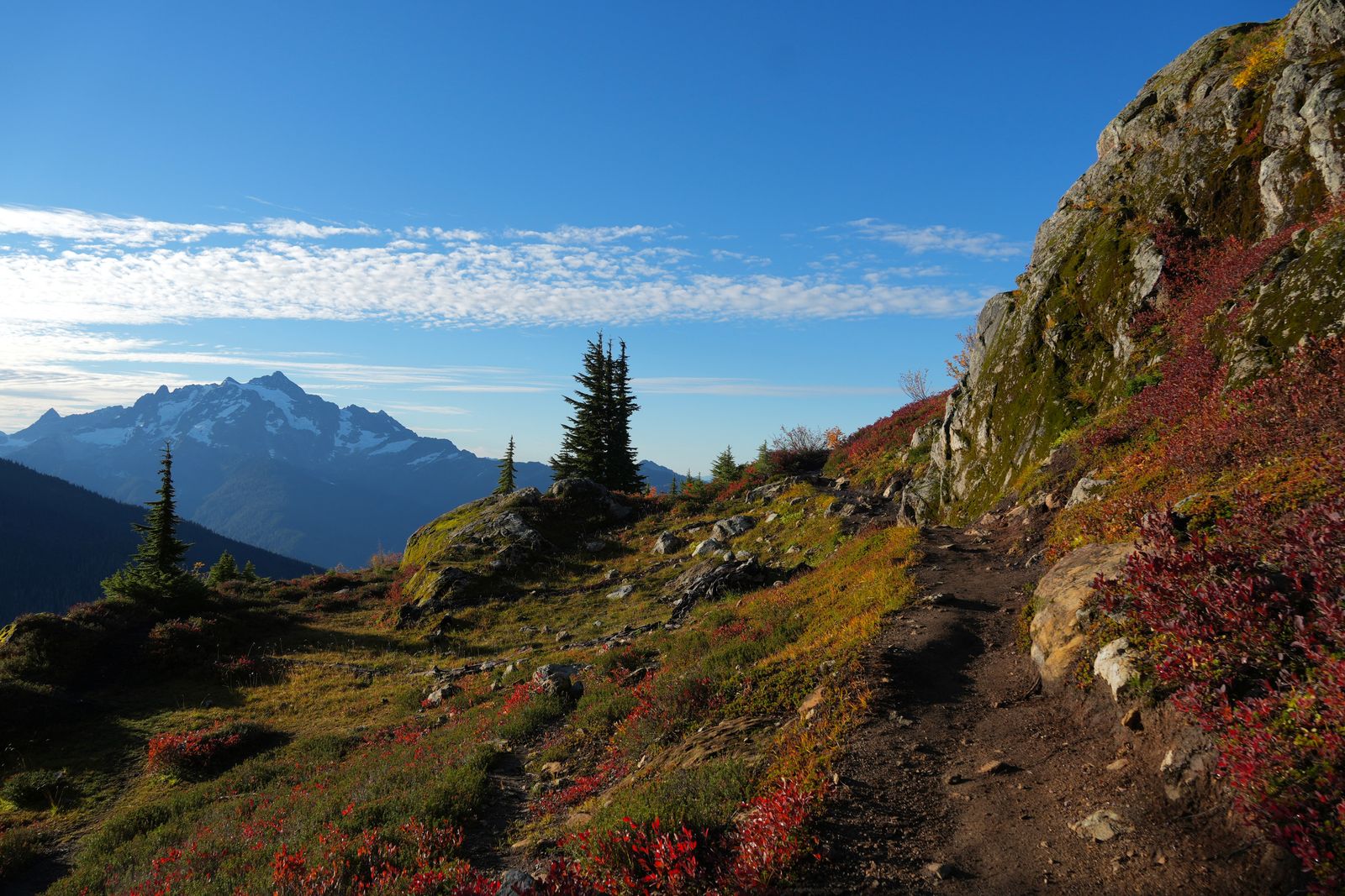 A mountainside trail below steep rock and snow-streaked peaks, Yellow Aster Butte