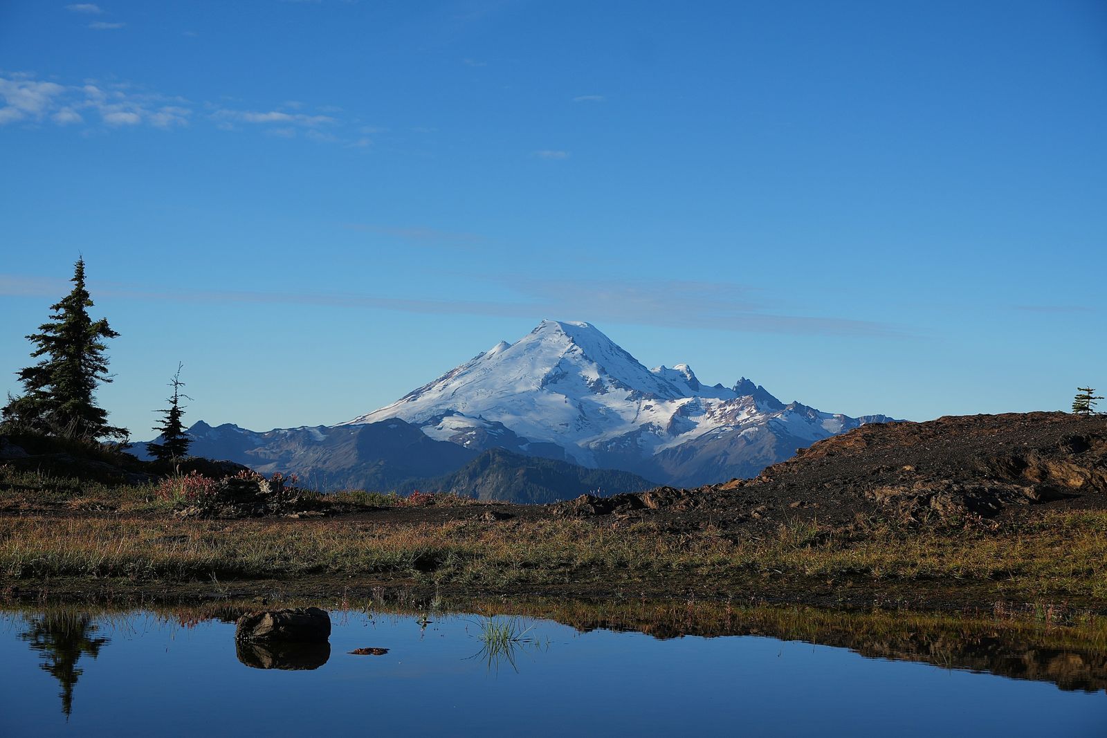 Mount Baker beyond a tarn reflecting trees and sky, Yellow Aster Butte