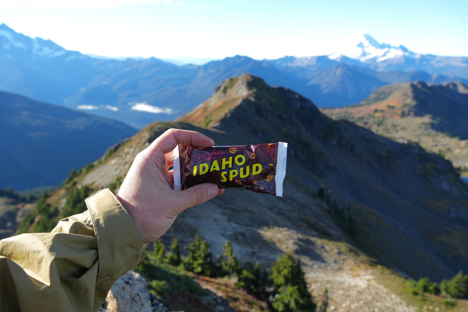A wrapped candy bar held in one hand beyond ridges, Yellow Aster Butte