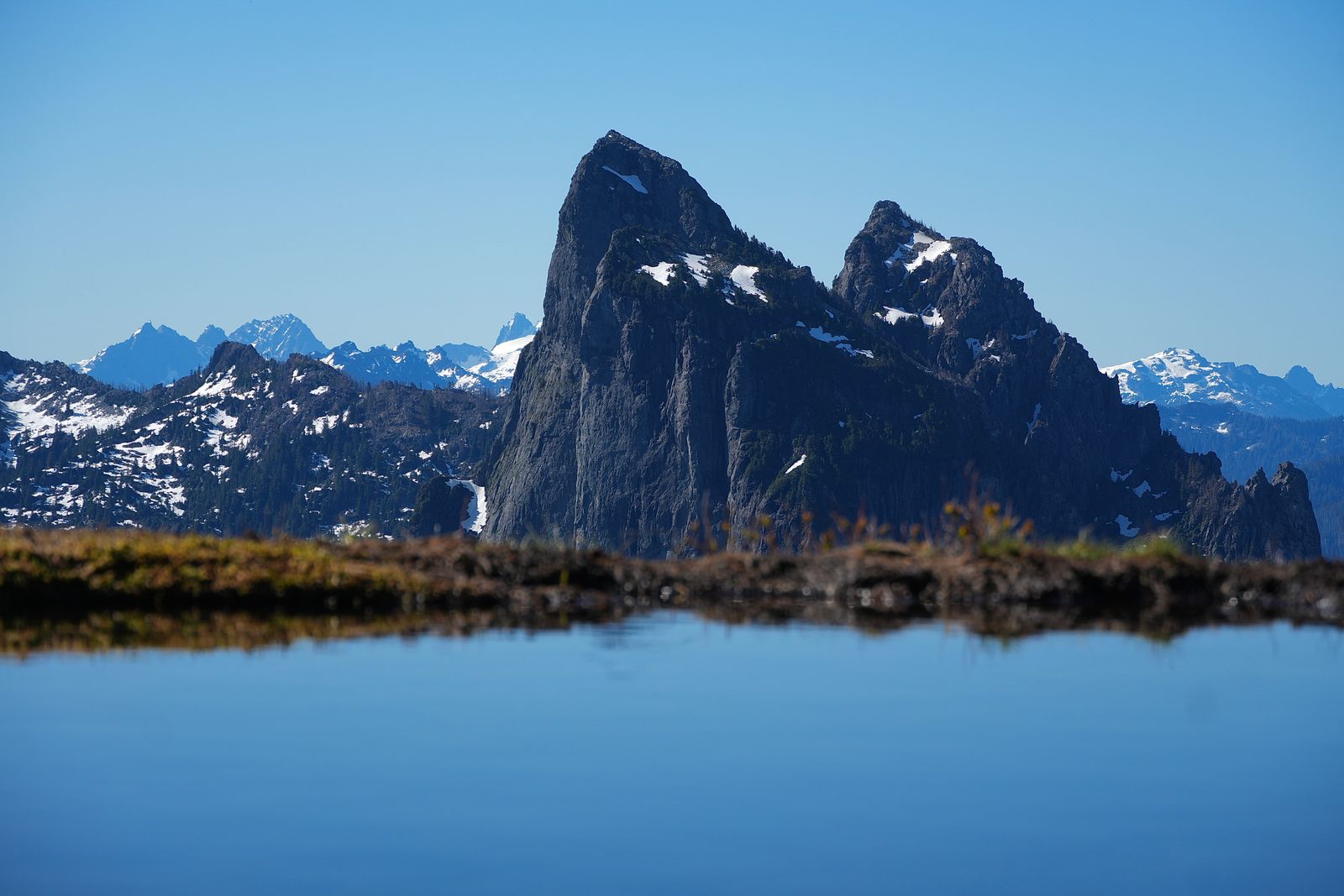 Snow-patched rocky peaks above a tarn and grassy bank, Gunn Peak