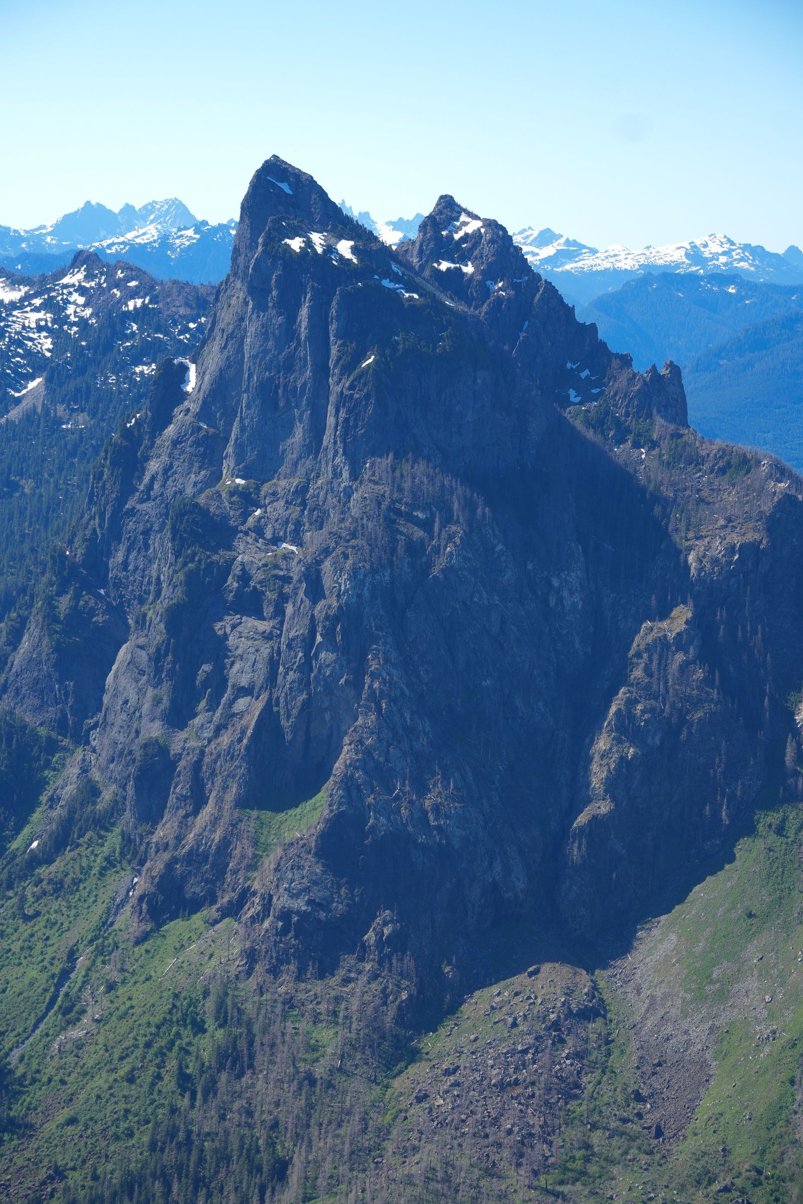 Jagged rocky peaks above green slopes with patches of snow, Gunn Peak