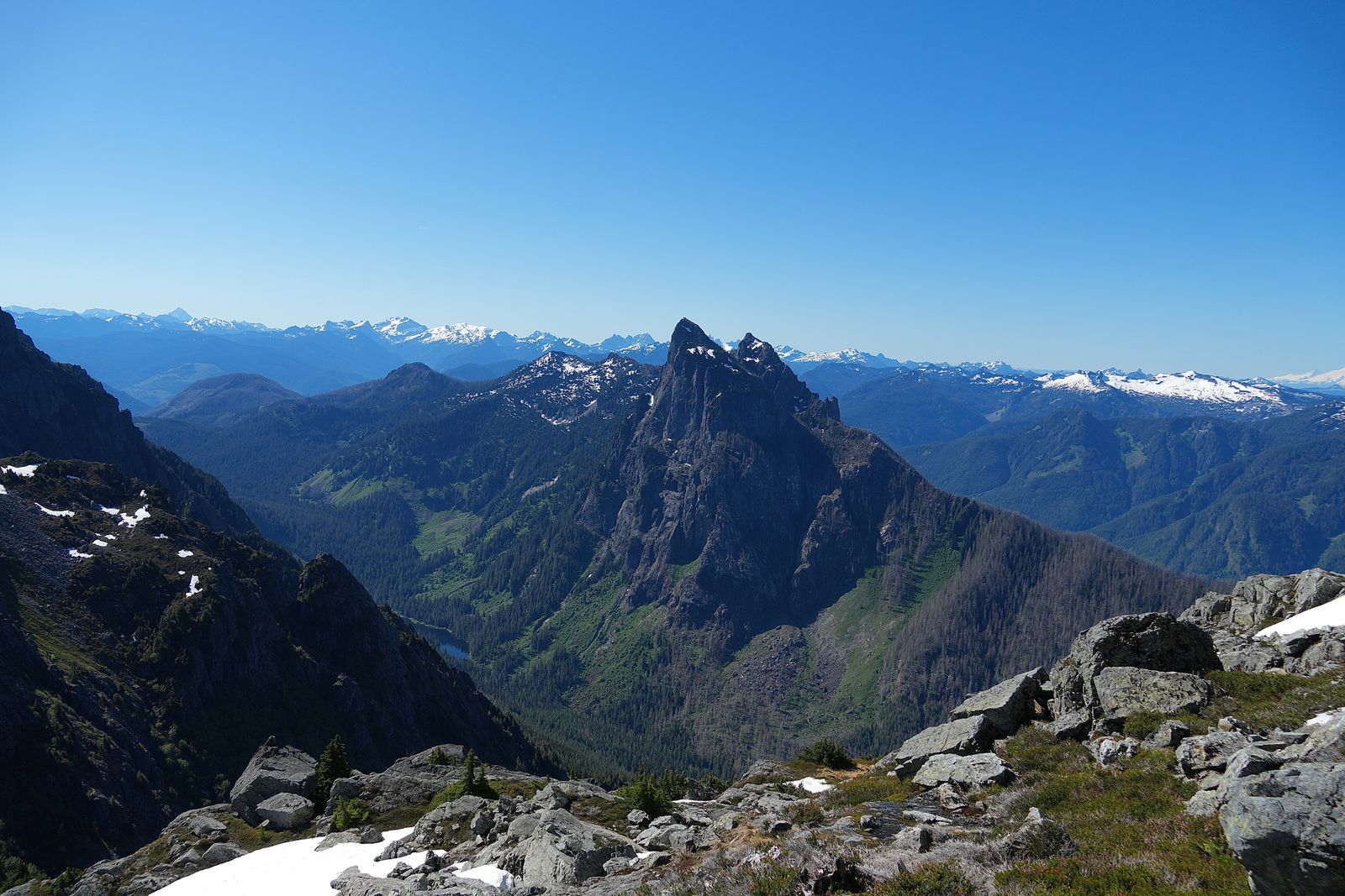 A rocky peak above forested slopes and snow-patched rocks, Gunn Peak