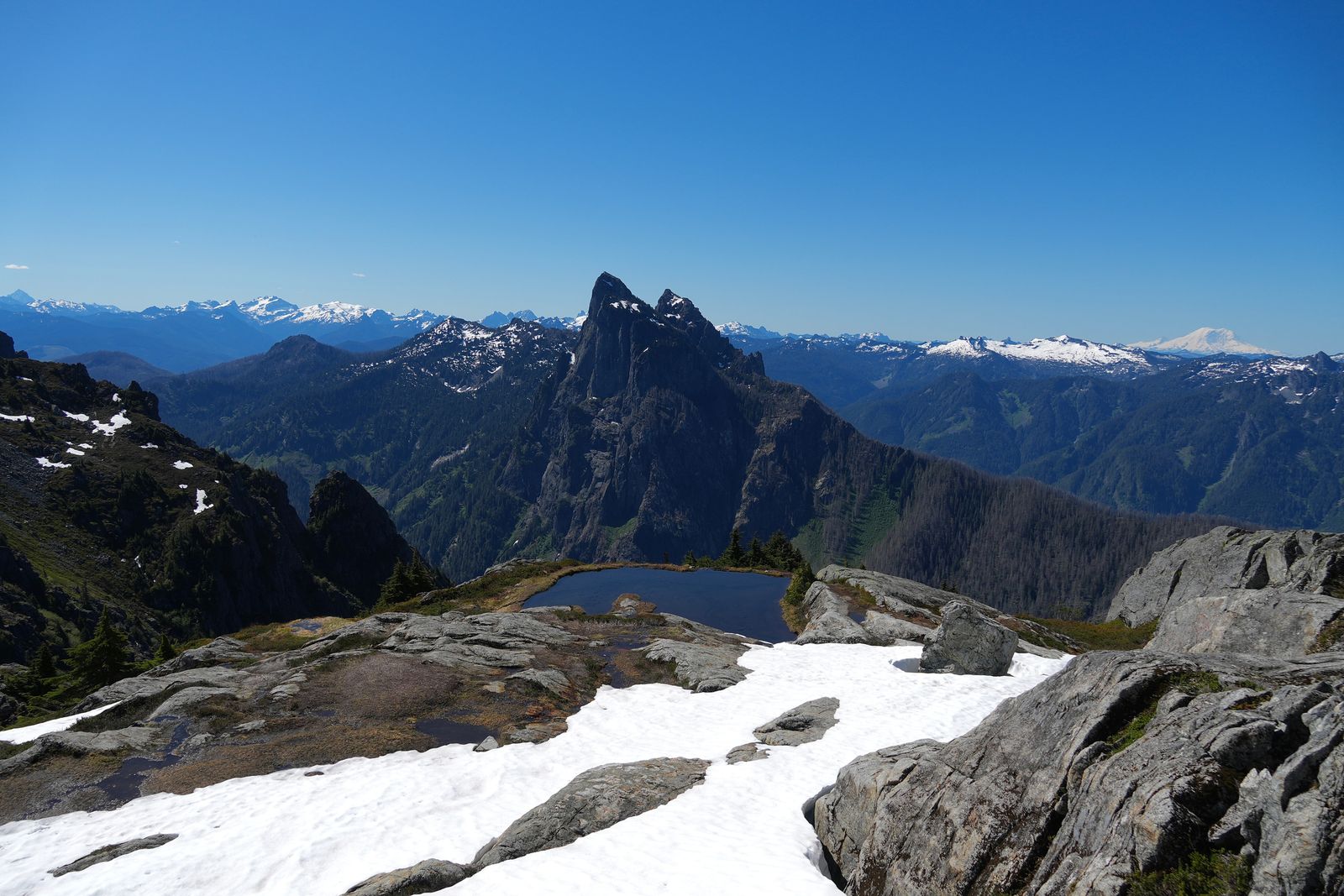 A jagged rocky peak beyond a tarn and snow patches, Gunn Peak