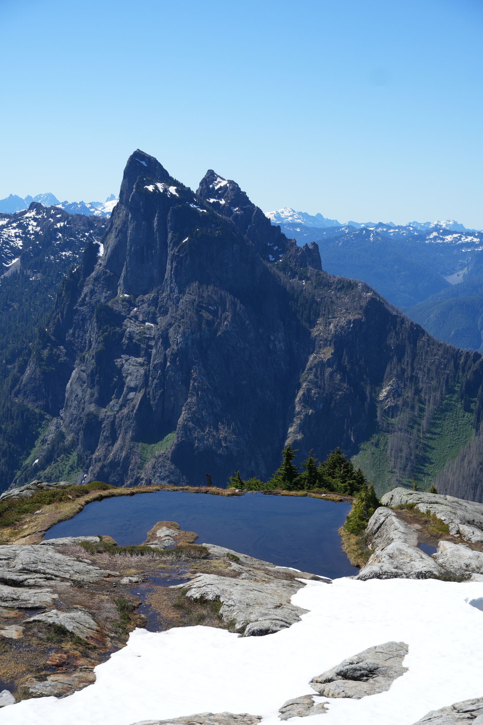 A jagged rocky peak above a tarn and snow-covered slabs, Gunn Peak