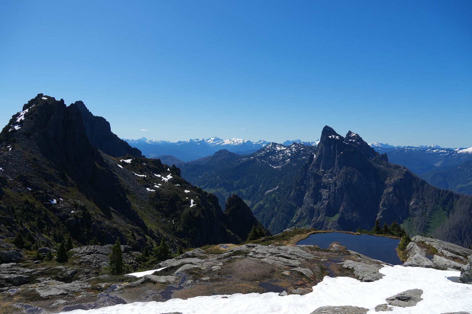 Rocky peaks above a tarn and snow-patched rock slabs, Gunn Peak