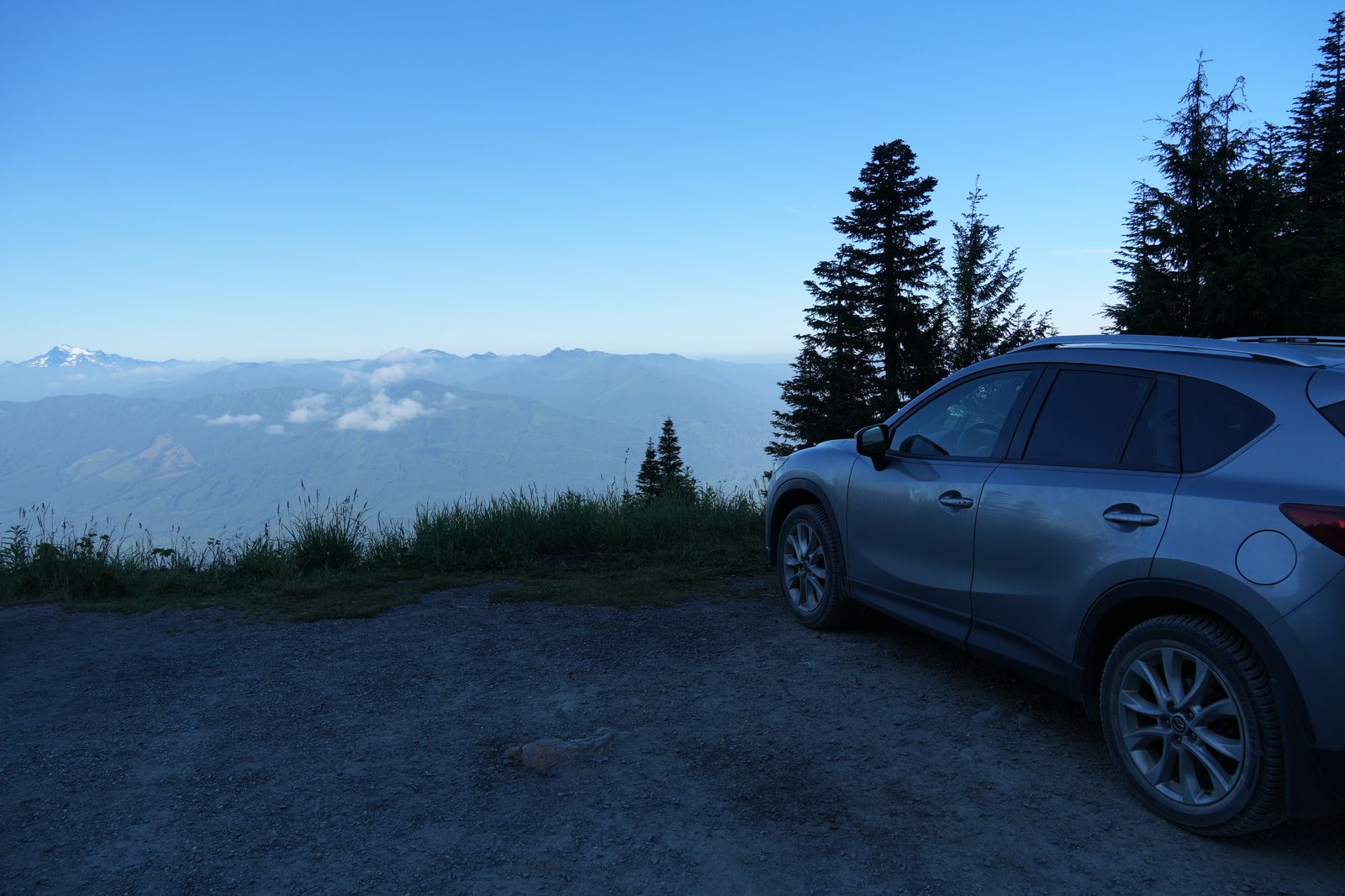 Silver SUV parked on gravel overlooking mountain ridges, Sauk Mountain