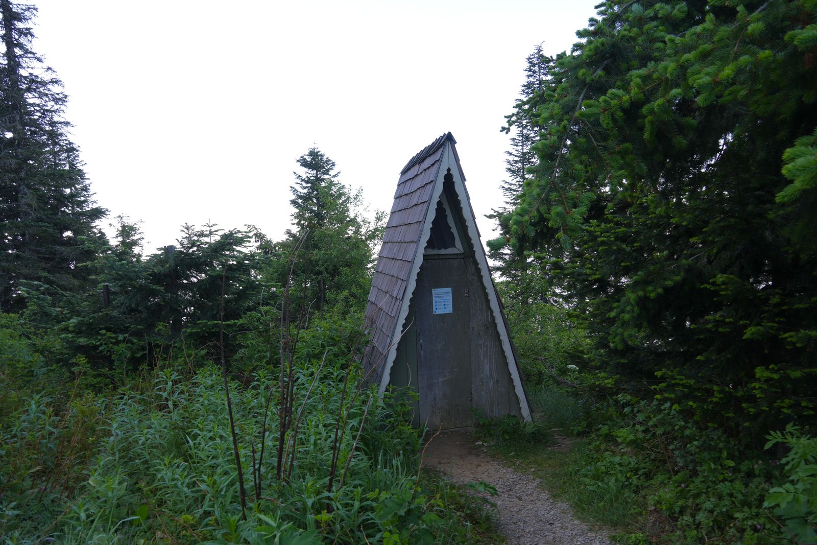 A-frame hut standing beside a dirt path among trees, Sauk Mountain