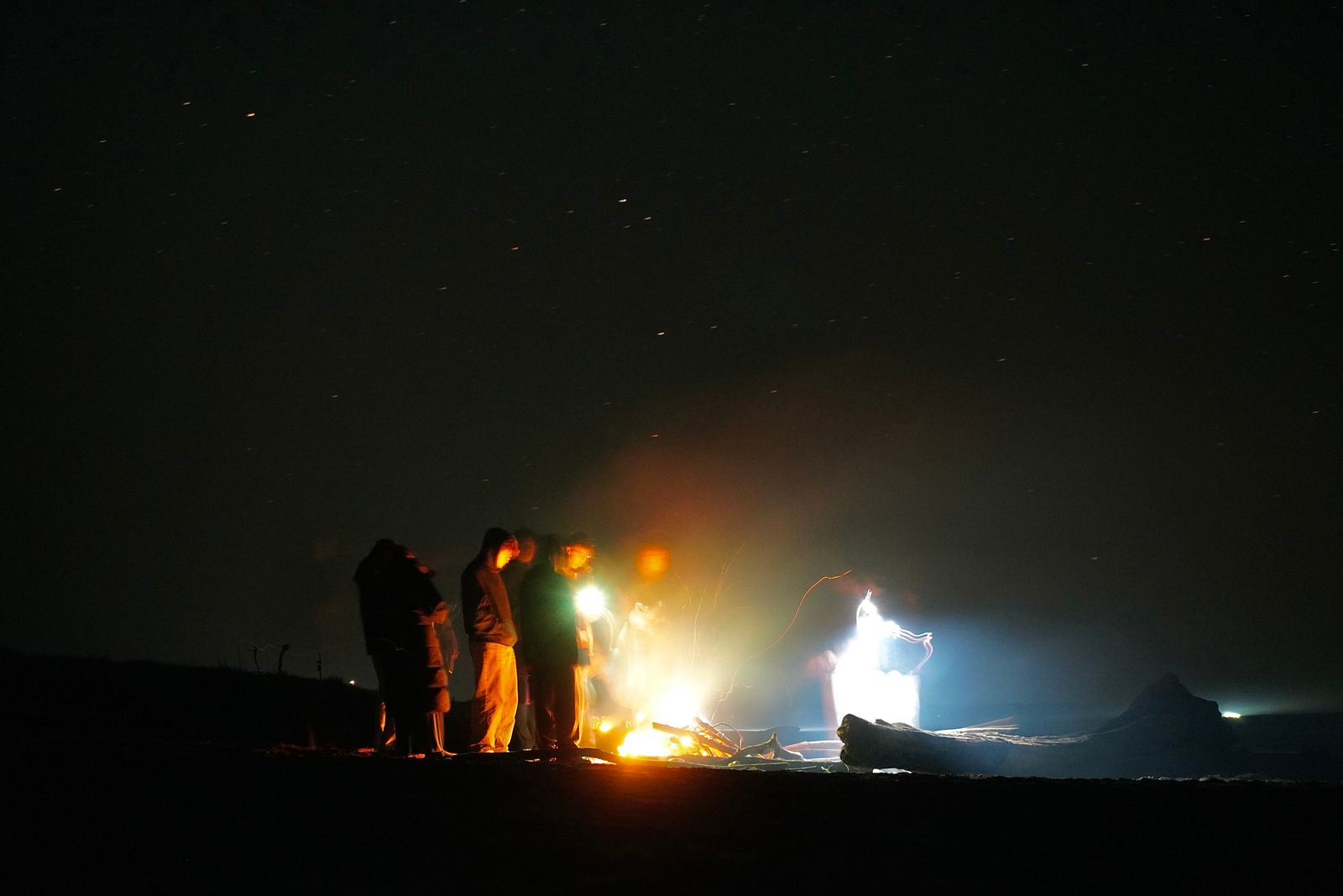 People around a fire beneath a starry sky at night, Westport