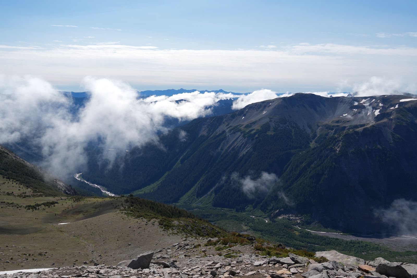 A snowy mountain ridge above a valley in low clouds, Sunrise