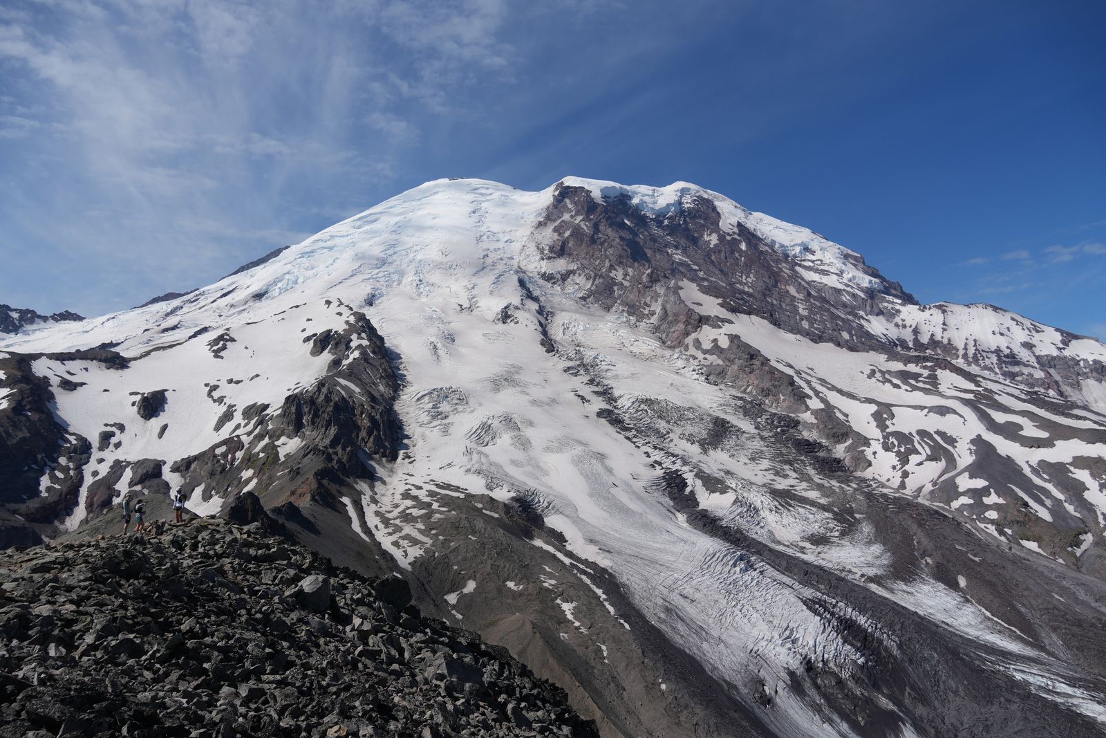 Mount Rainier above hikers on a rocky ridge, Sunrise