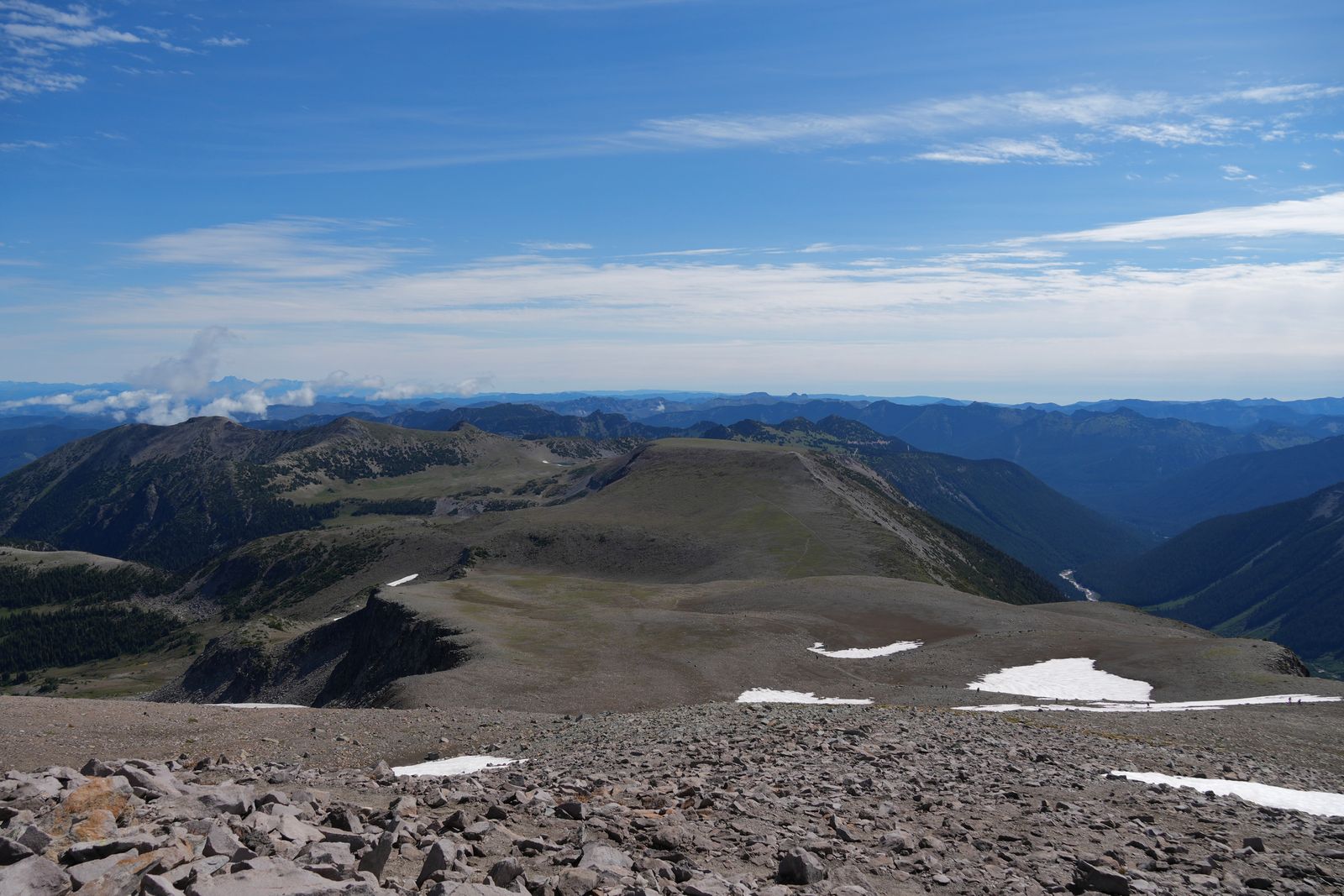 Mountain ridges beyond rocky slopes with patches of snow, Sunrise