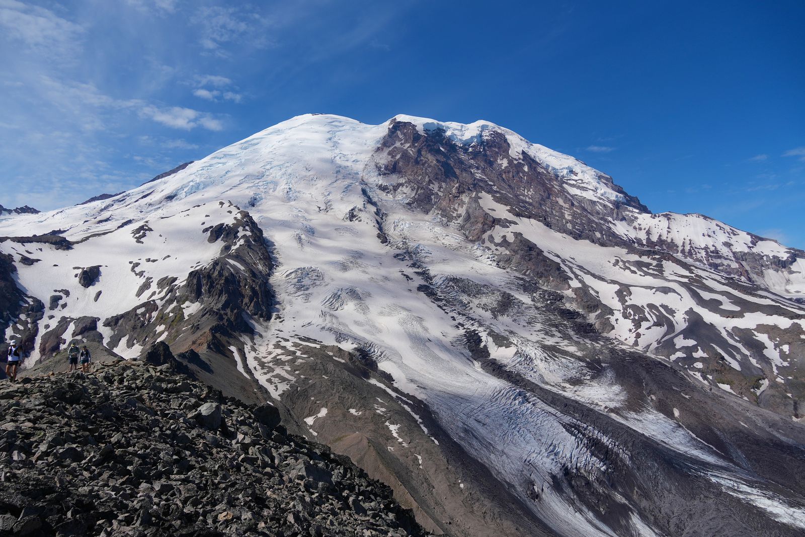 Mount Rainier above hikers on a rocky ridge, Sunrise