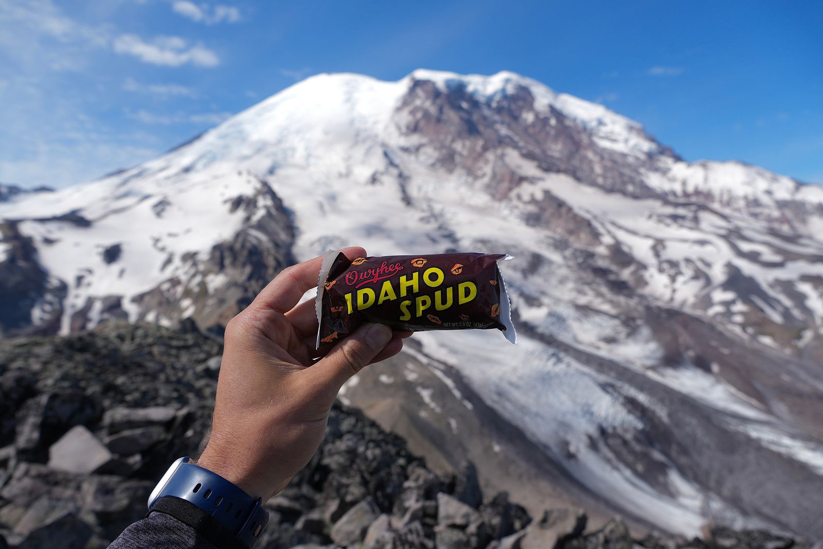 A wrapped candy bar held below Mount Rainier, Sunrise