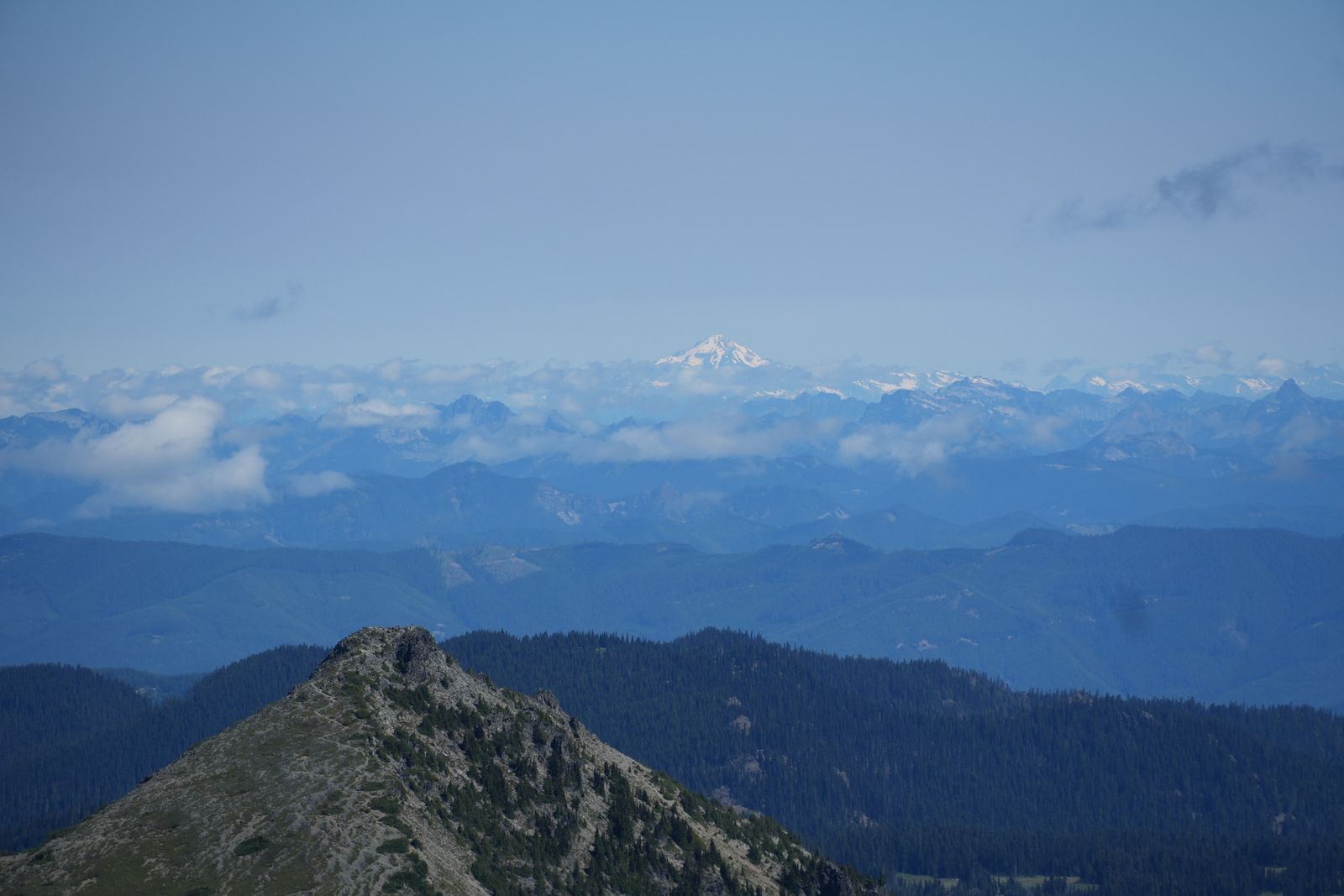 Mountain ridges beyond a rocky crest toward a snow-covered peak, Sunrise