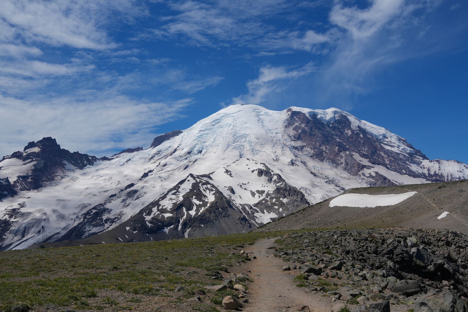 Mount Rainier above a rocky trail and sparse vegetation, Sunrise
