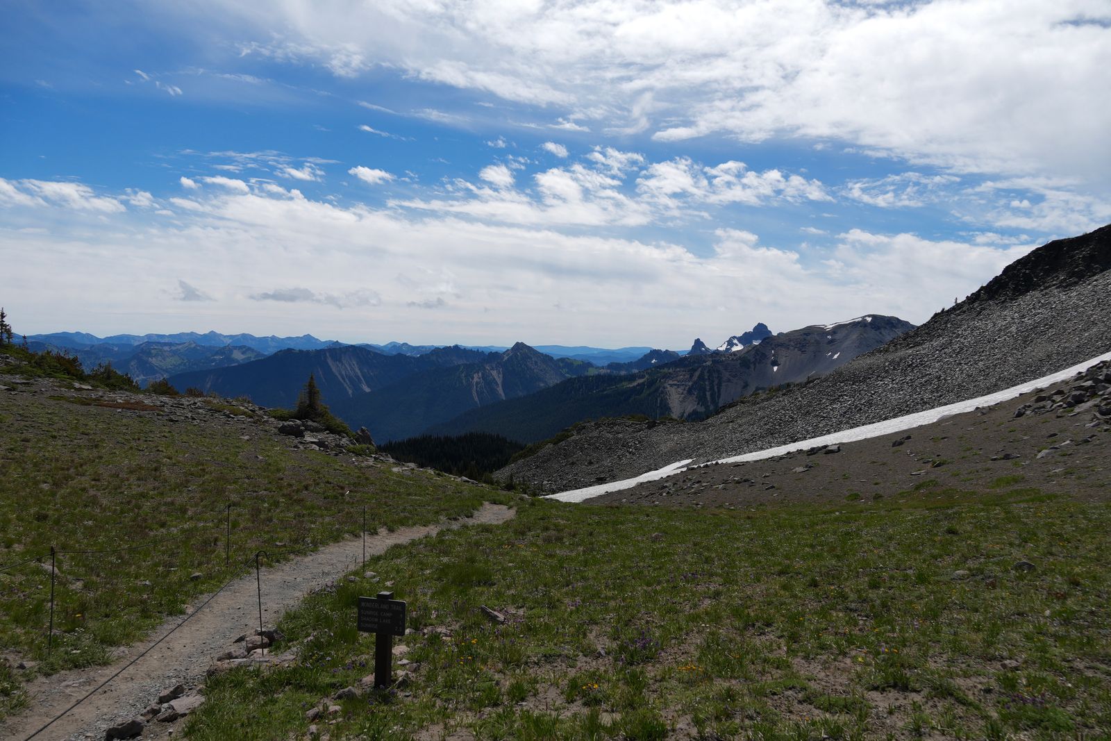 Mountain ridges beyond a meadow trail and snow-streaked slope, Sunrise