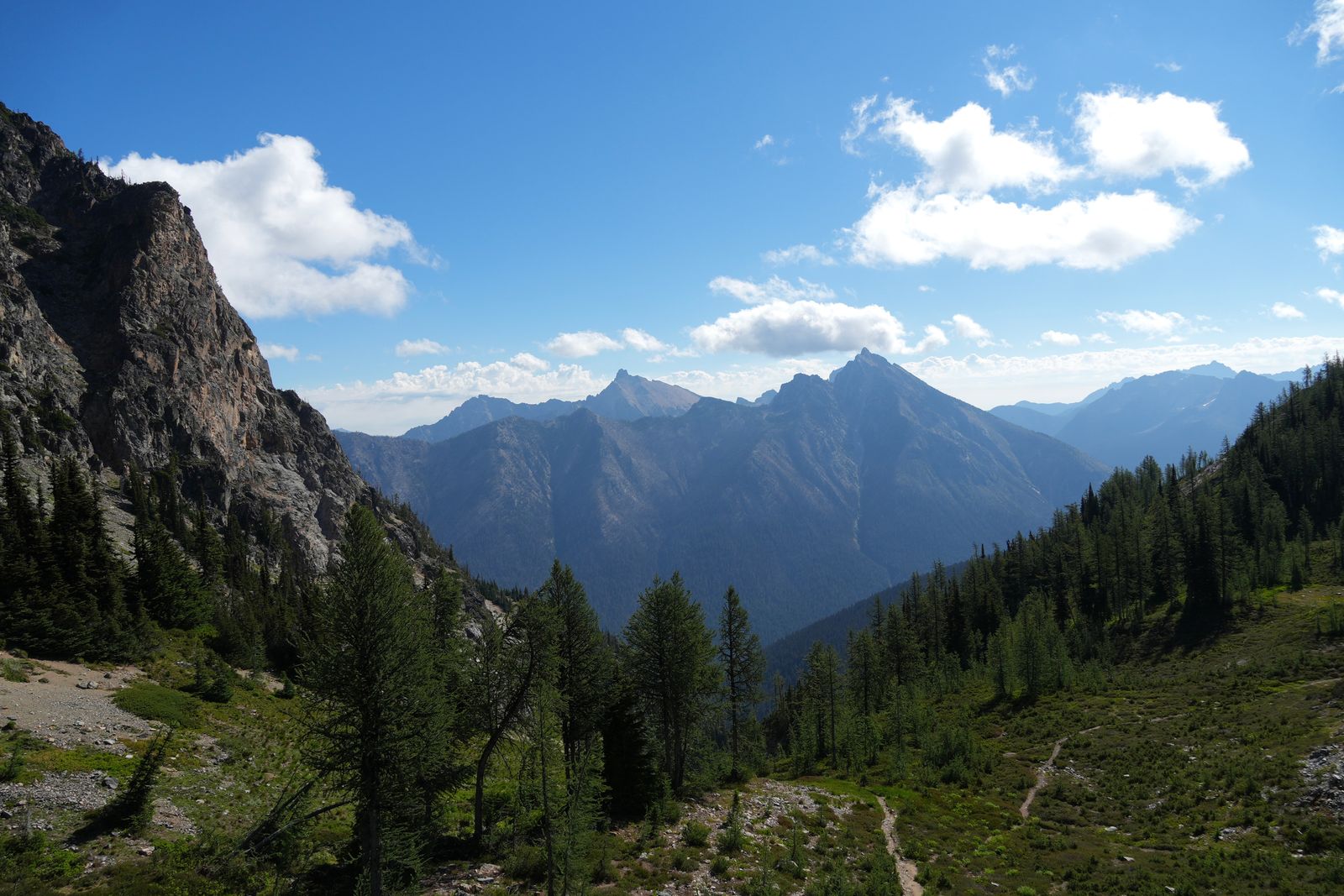 North Cascades peaks beyond wooded slopes and a narrow trail, Washington Pass