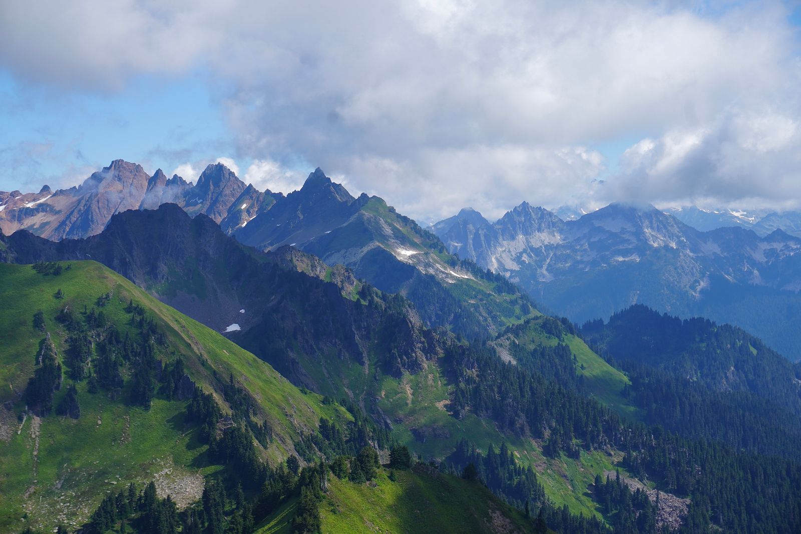 Jagged mountain ridges with snow patches under low clouds, North Cascades