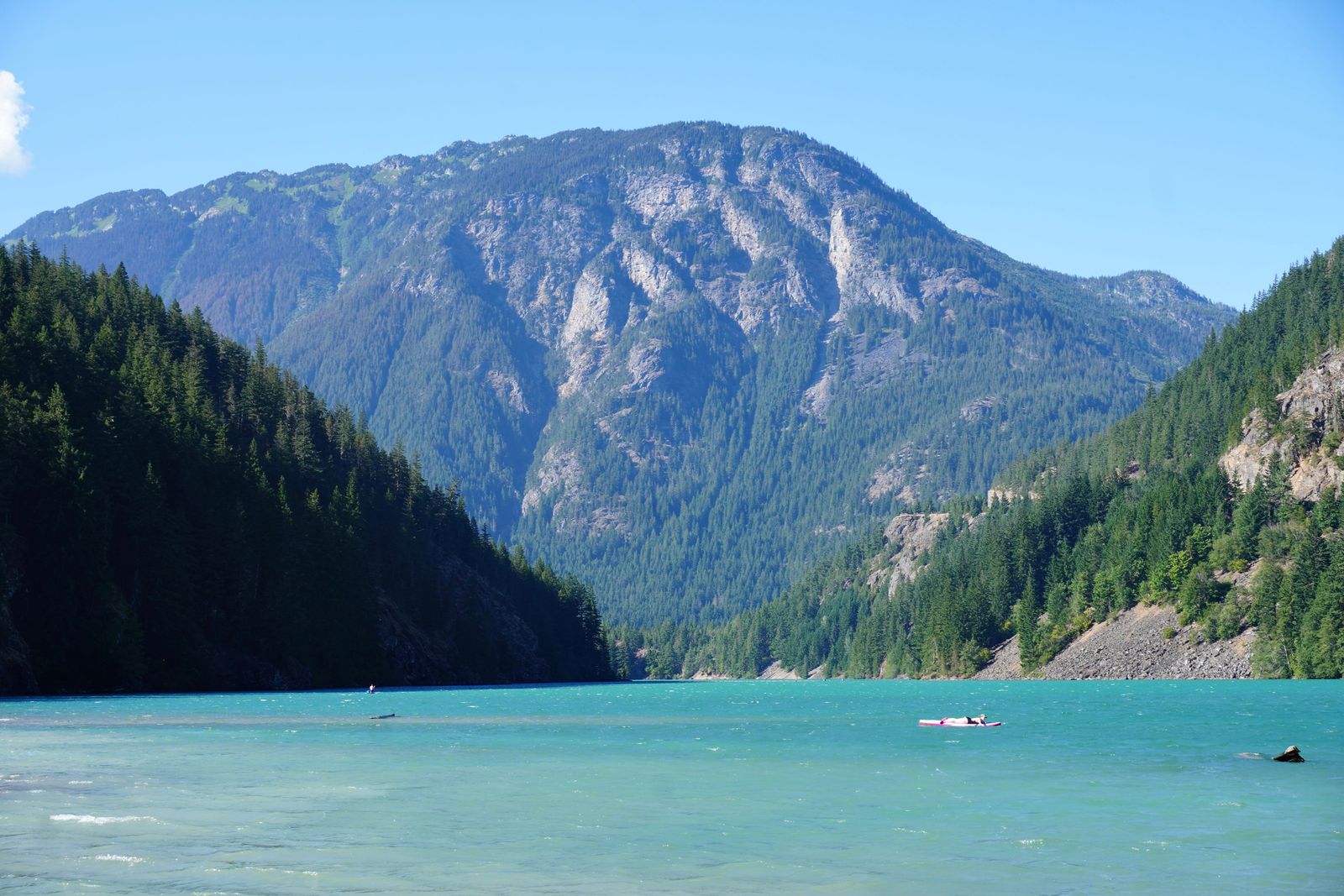 Turquoise lake with a paddleboard below a rocky mountain, North Cascades