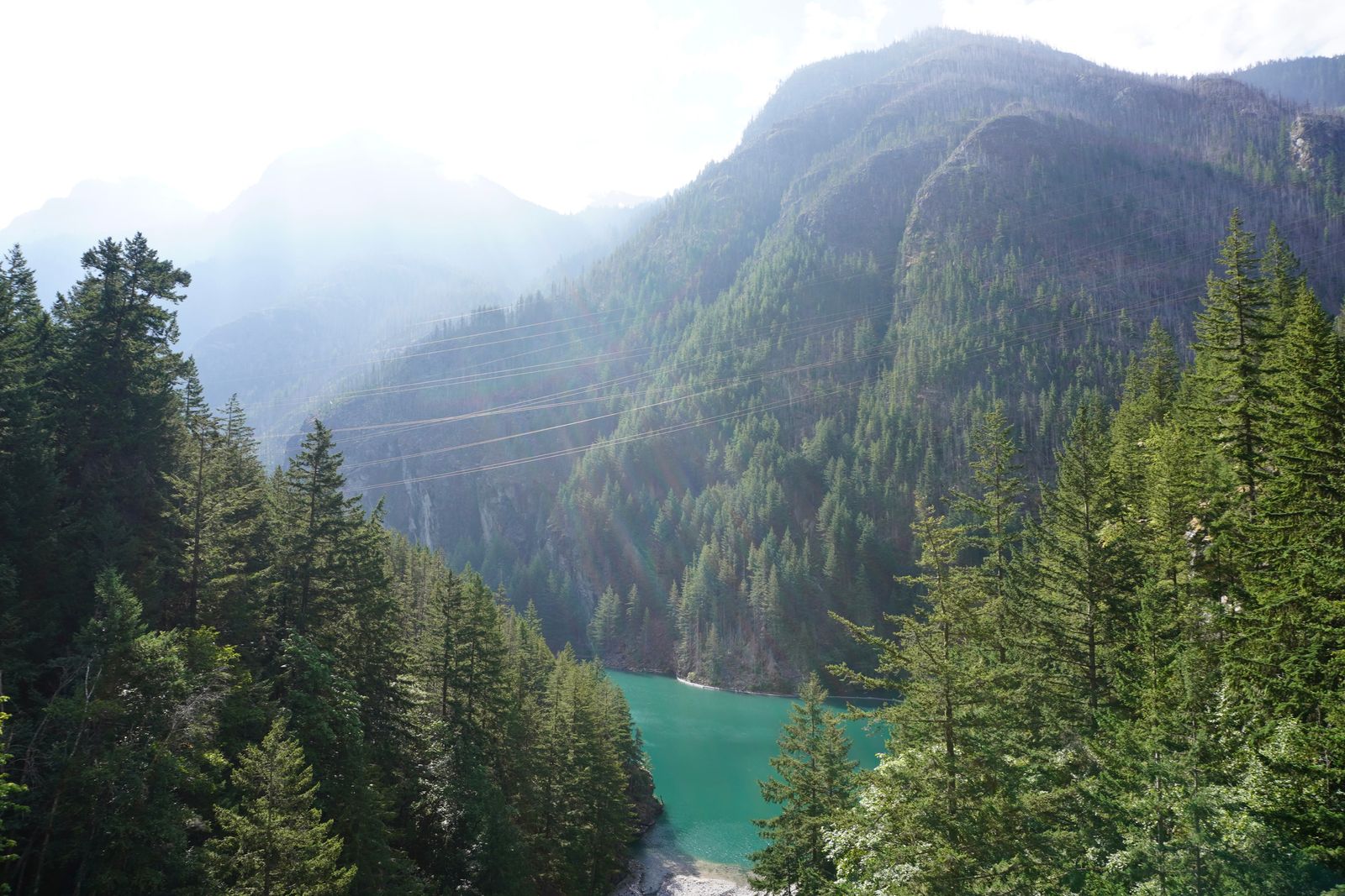 Turquoise lake among trees beneath steep forested slopes, North Cascades