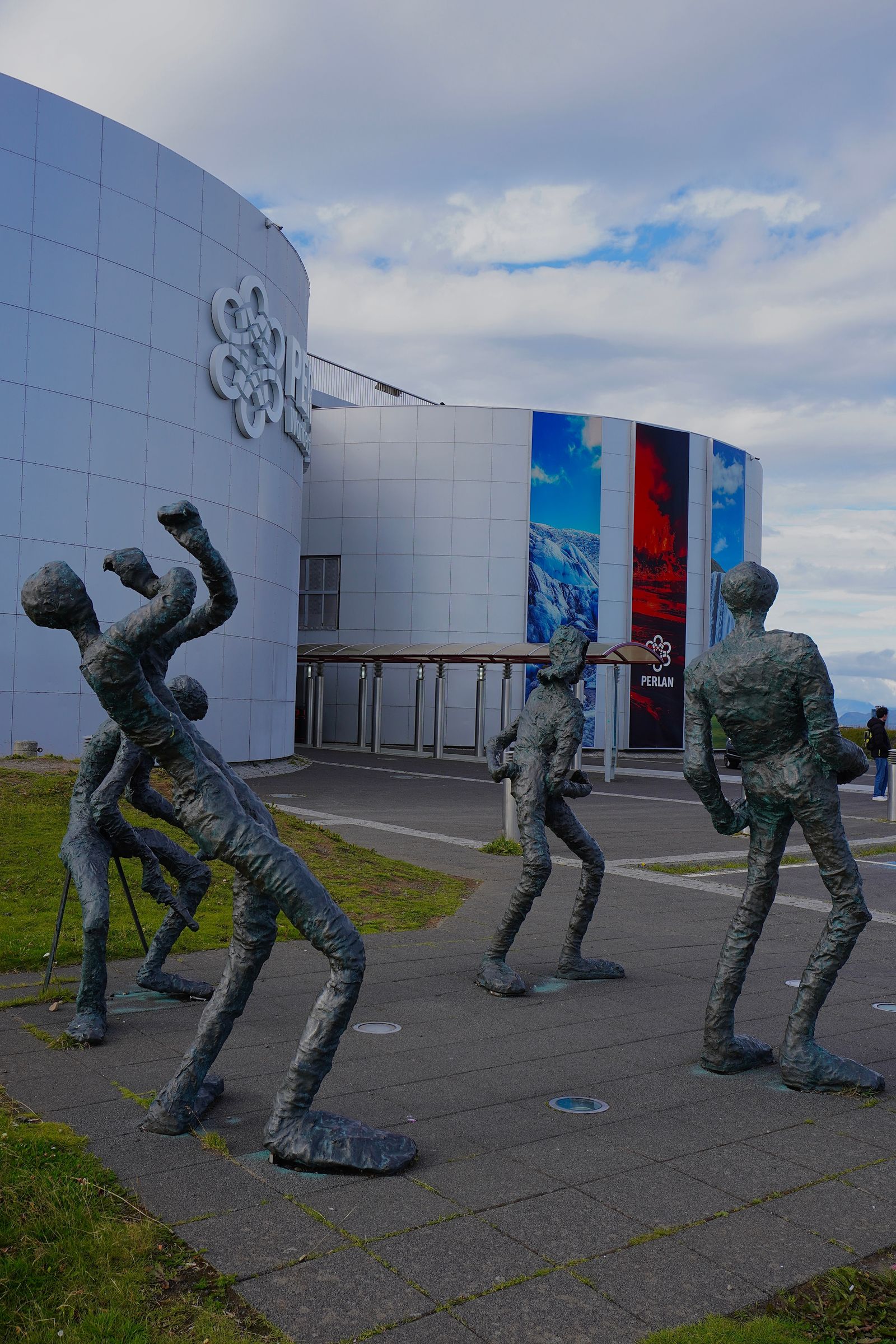 Human-shaped sculptures outside a curved white building in Reykjavik