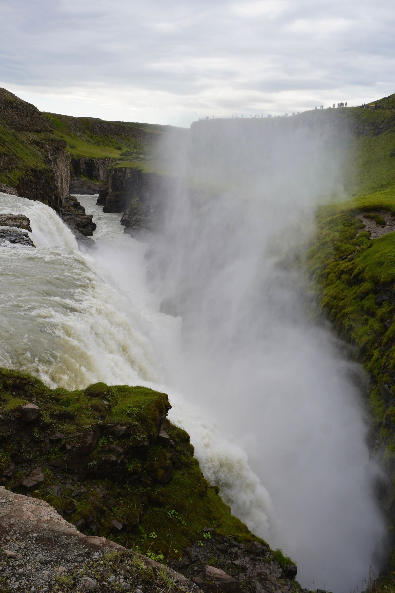 Waterfall dropping into a rocky gorge filled with spray, Bláskógabyggð