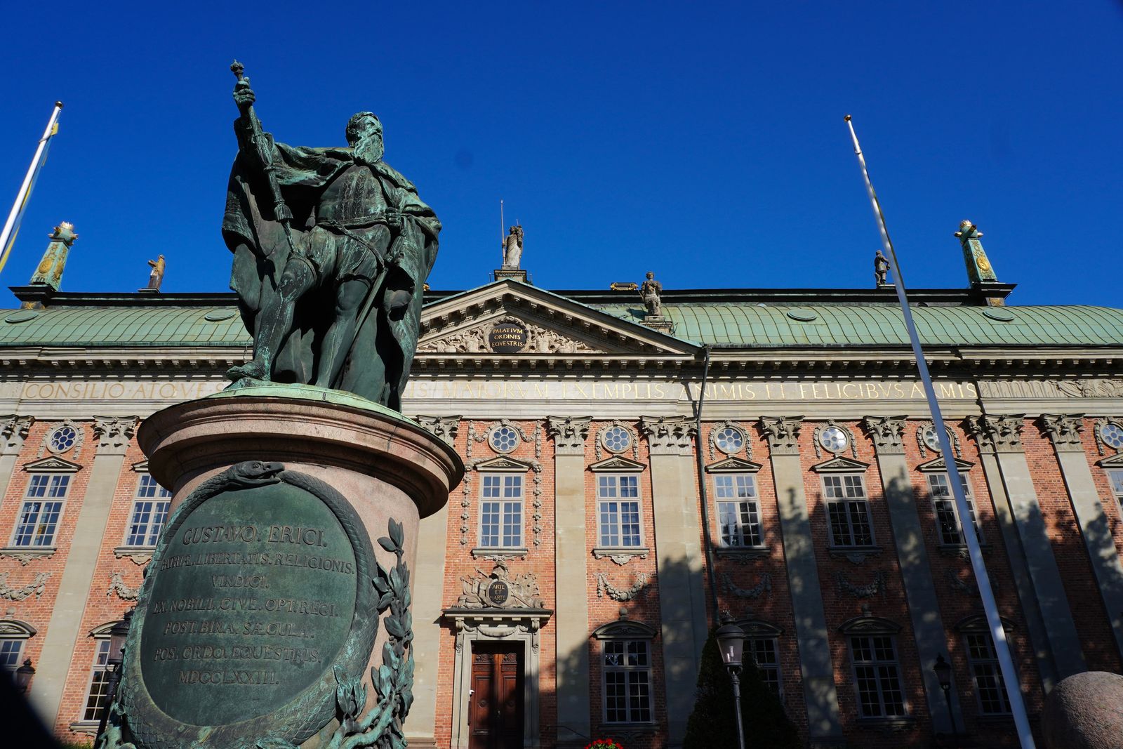 Bronze statue on a pedestal before an ornate brick building, Stockholm