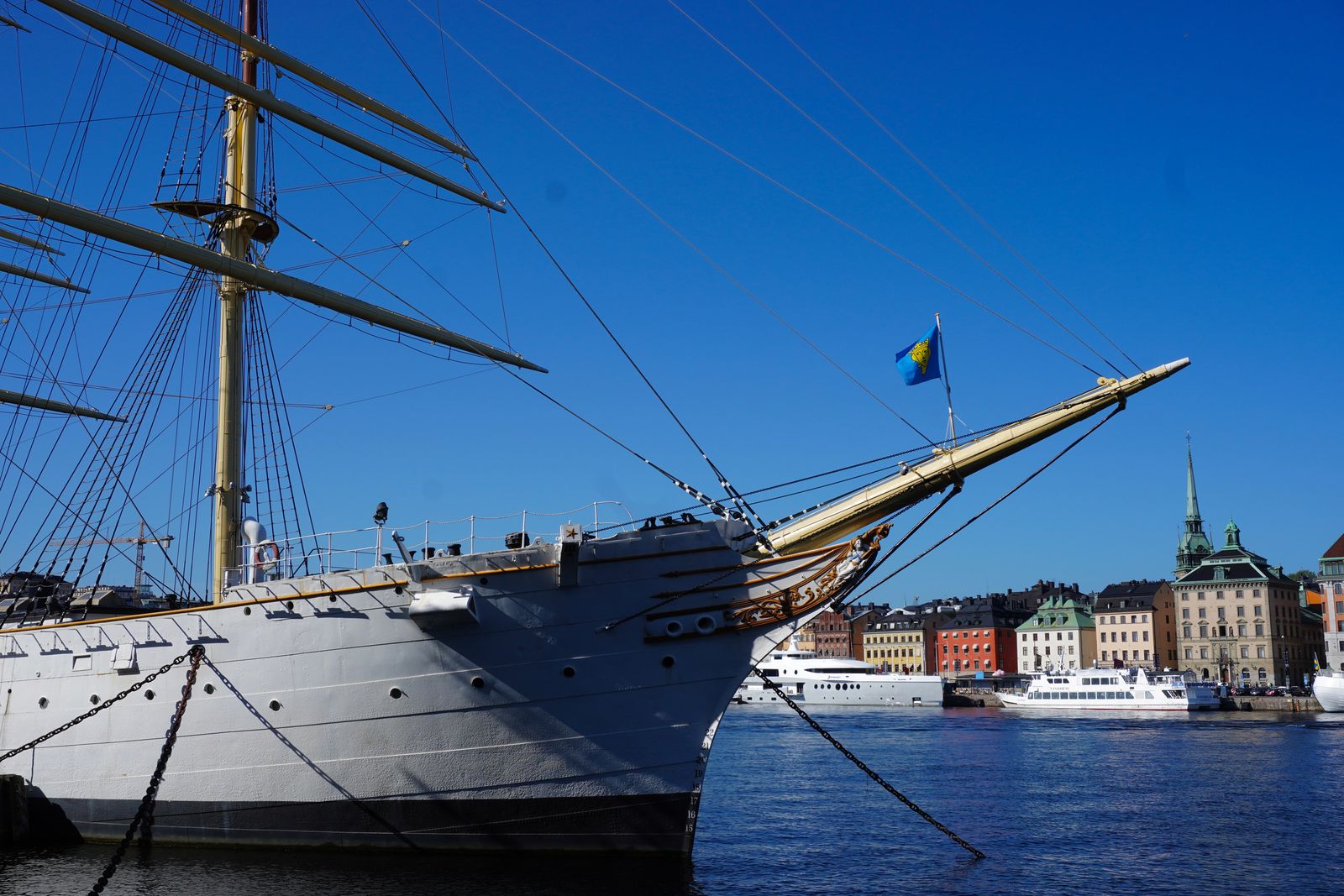 Sailing ship moored beside boats and Stockholm waterfront buildings