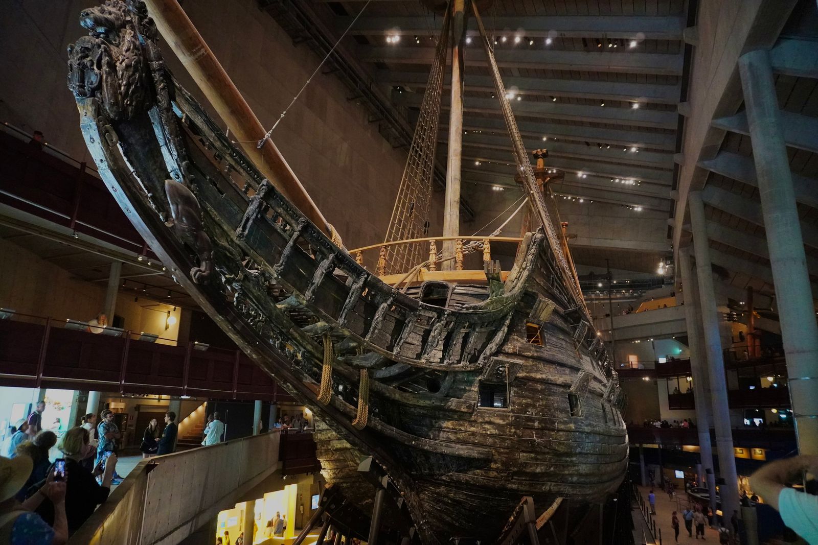 Wooden ship with carved figures beside indoor visitor walkways, Stockholm