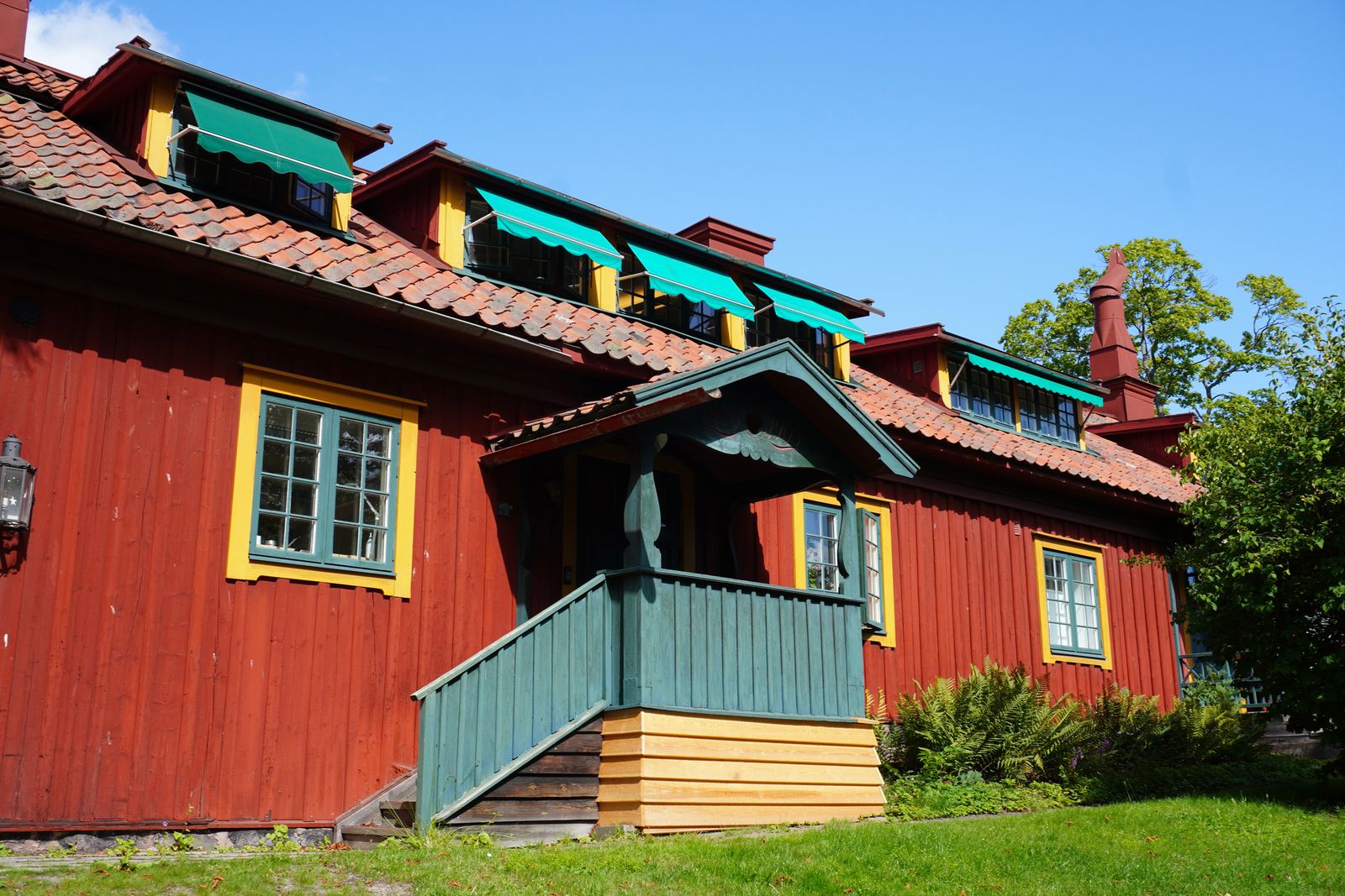 Red wooden building with a covered porch and green awnings, Stockholm