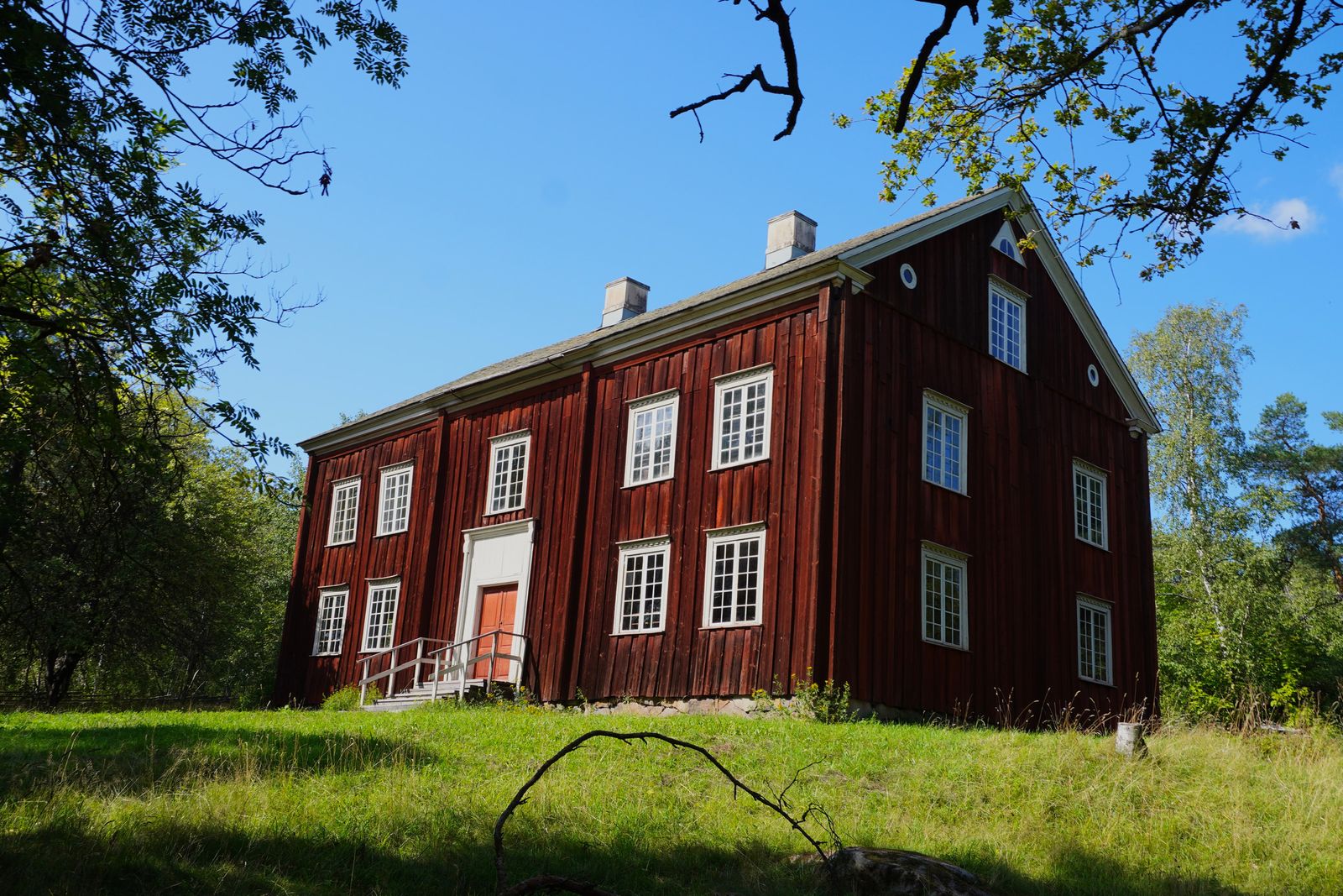 Red wooden building with an orange door beside grass, Stockholm