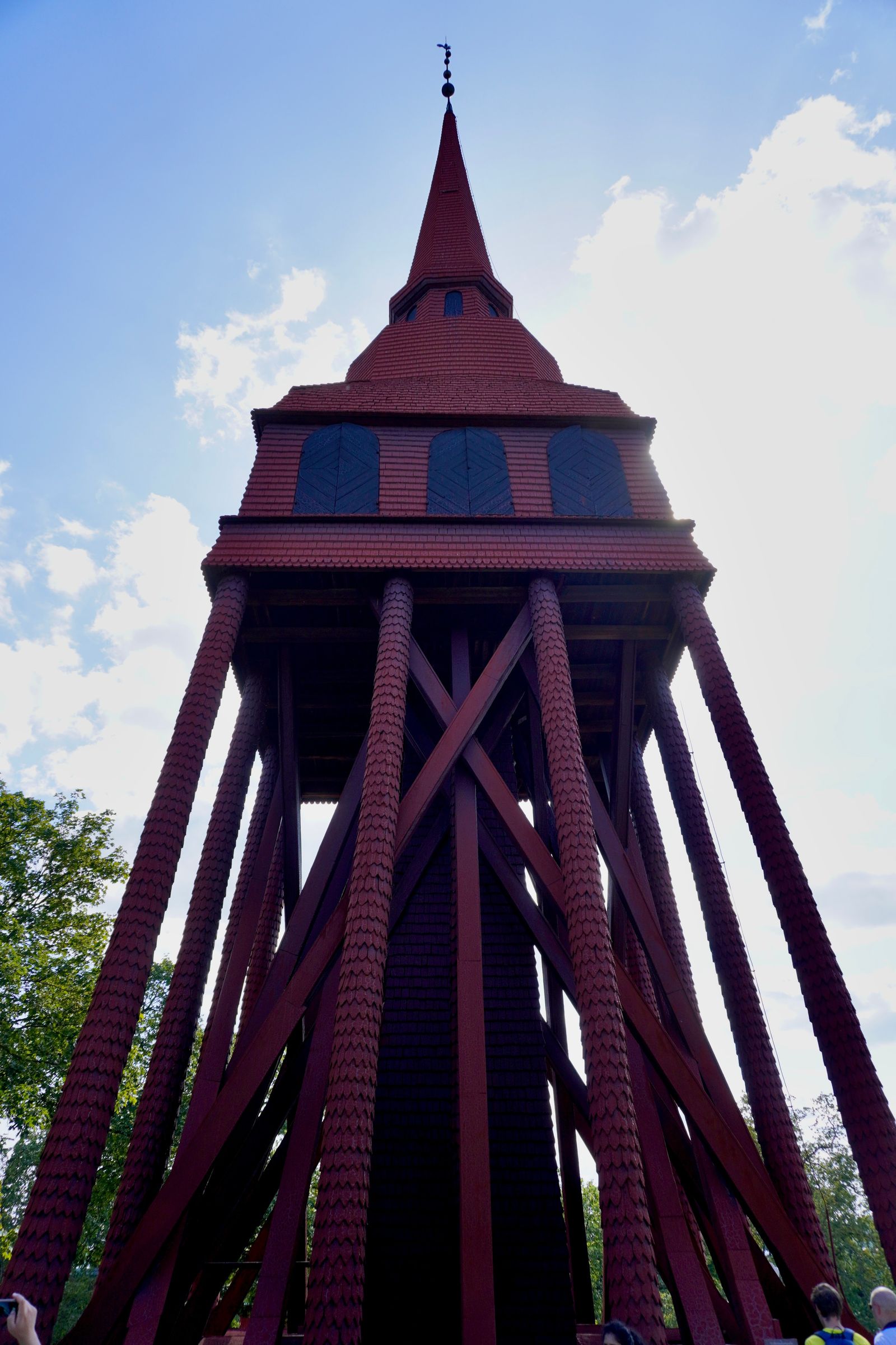 Red wooden tower with blue shutters rising above trees, Stockholm