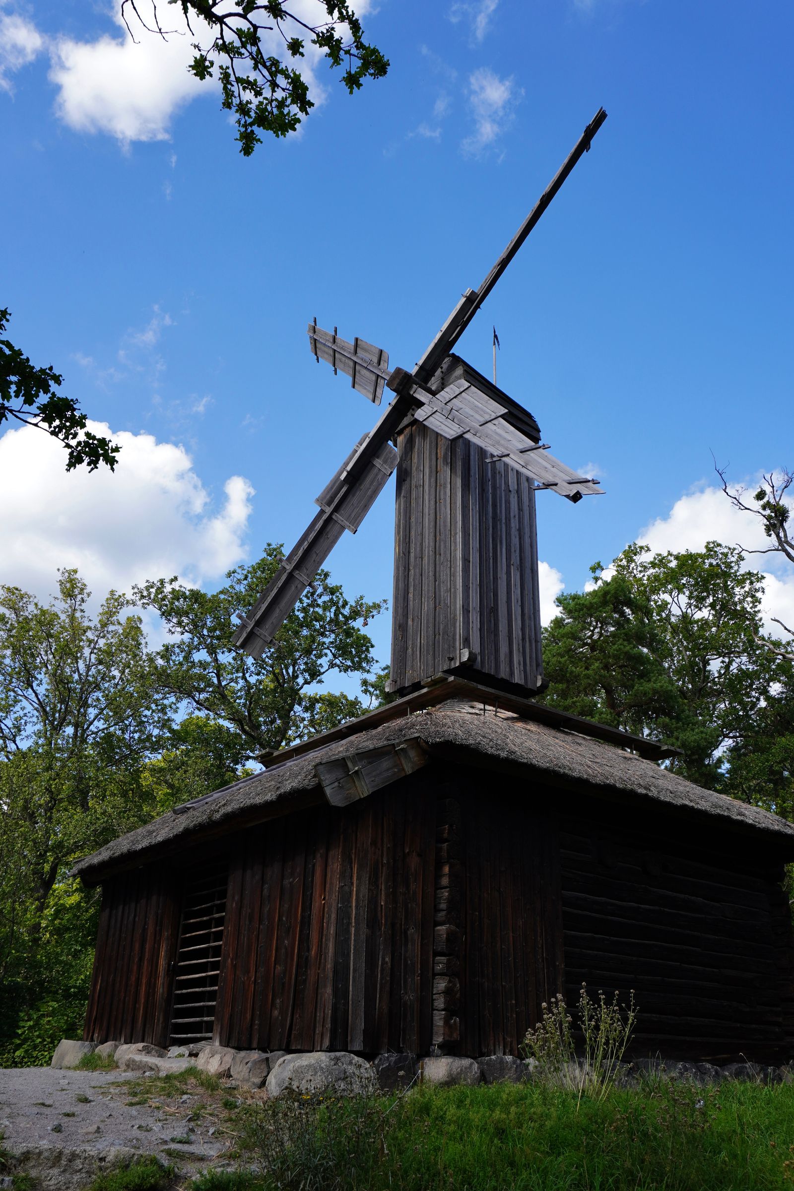 Wooden windmill above a thatched building among trees, Stockholm