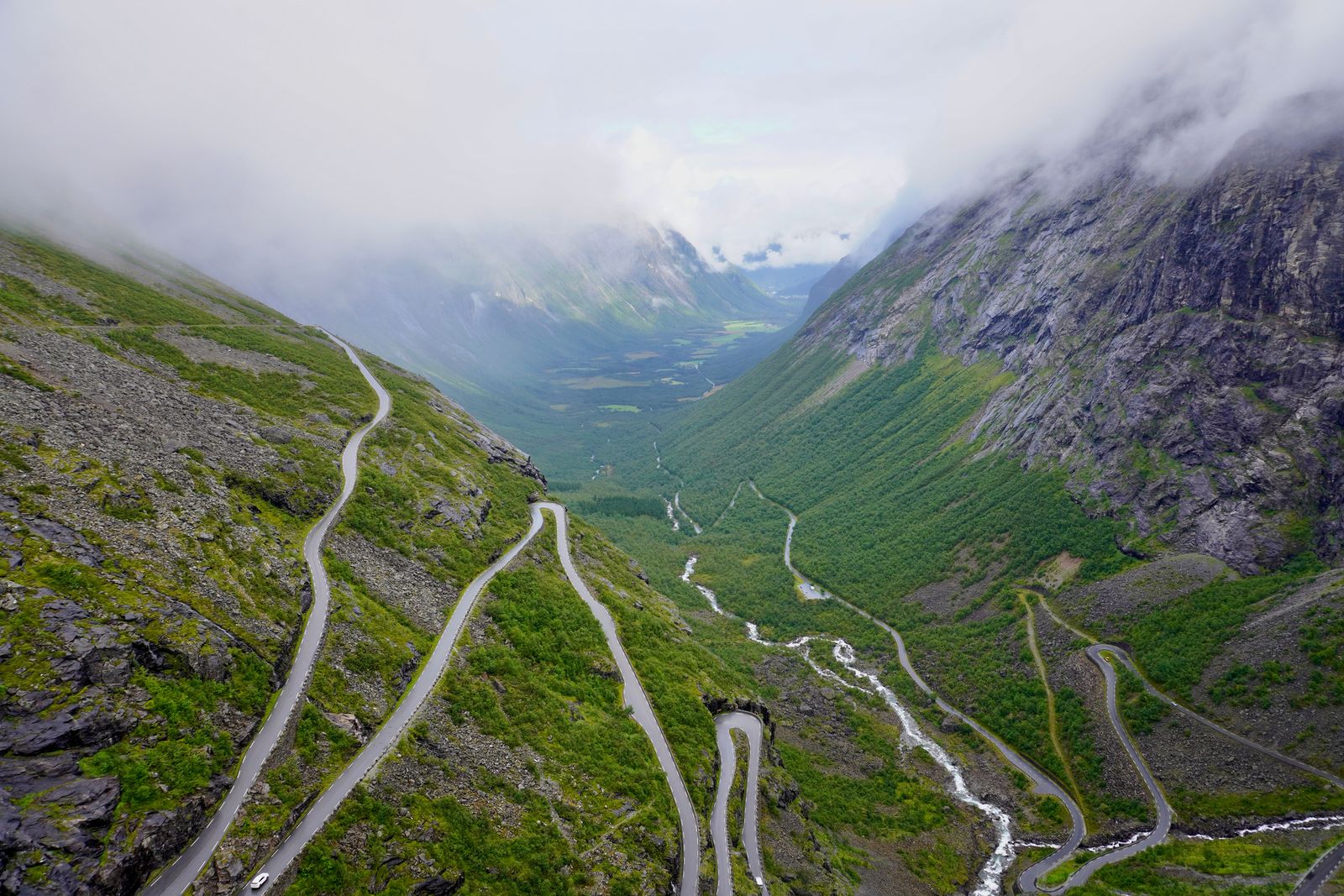 Trollstigen hairpin road and white-water stream under low clouds