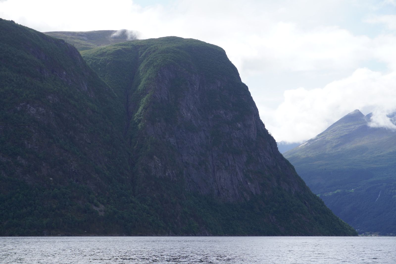 Steep mountain above water with a pointed peak beyond, Geiranger