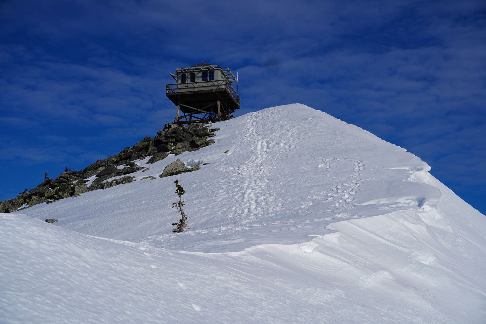 Wooden lookout on a snow-covered summit above rocky slopes, Western Washington