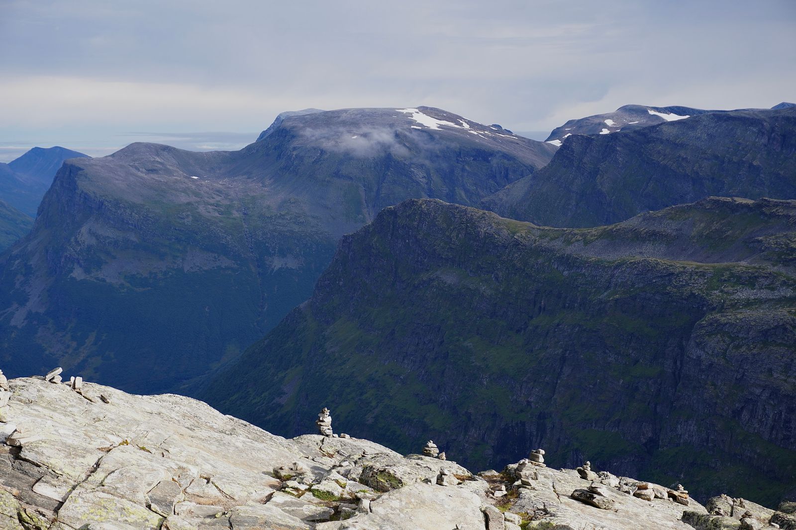 Rocky mountains in low cloud beyond small stone cairns, Geiranger