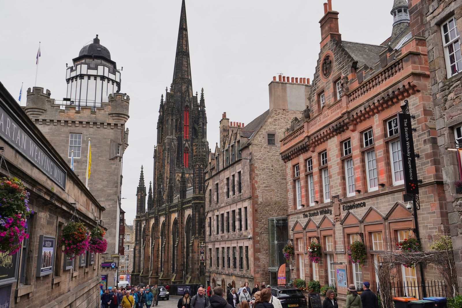 Stone buildings and a spire along a sloping street, Edinburgh Town