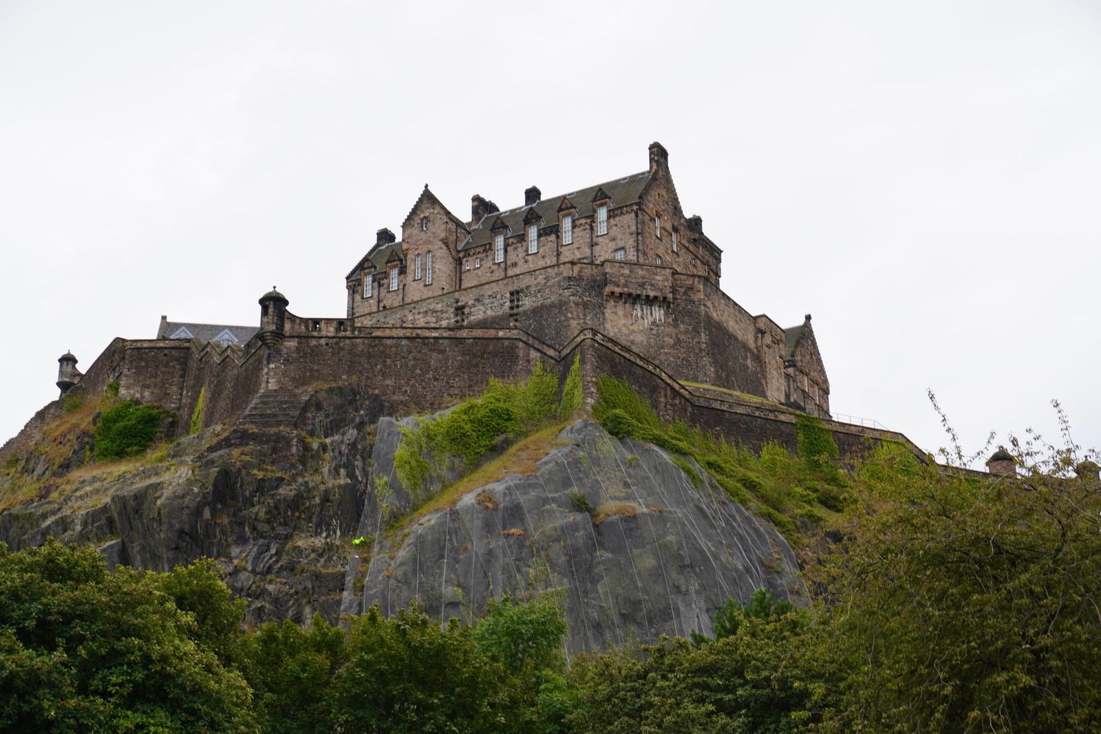 Stone castle above rocky slopes and green shrubs, Edinburgh Town
