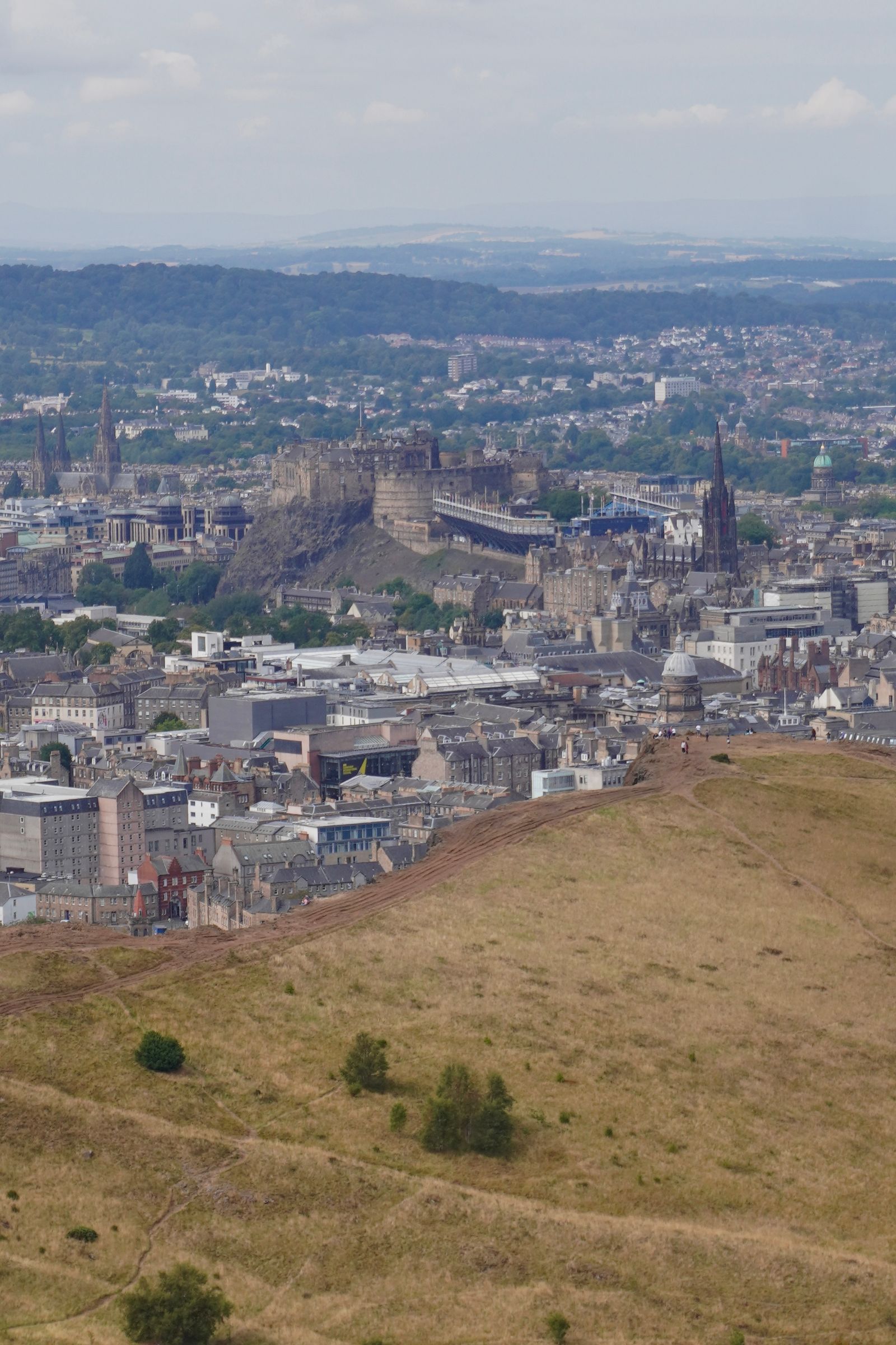 Edinburgh Town and a stone castle beyond a grassy hillside