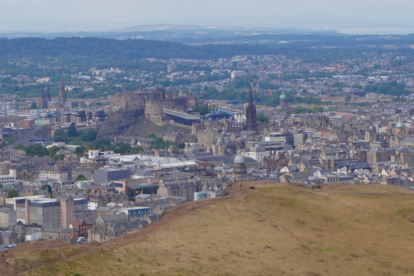 Edinburgh Town beyond a grassy ridge crossed by footpaths