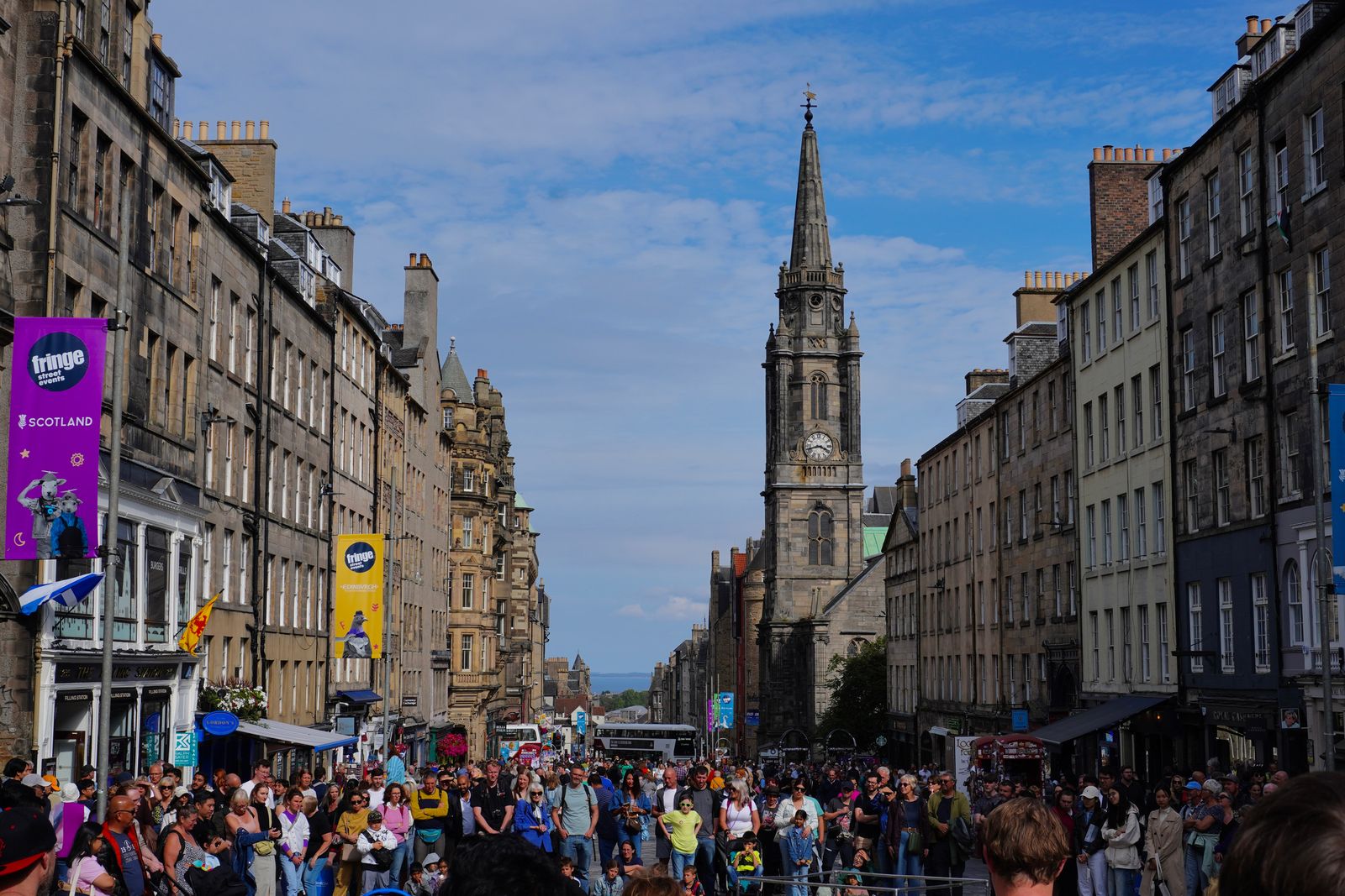 Stone clock tower above a crowded street in Edinburgh Town