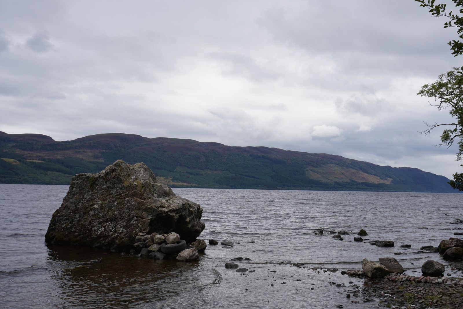 Loch Ness with a shoreline boulder under grey clouds