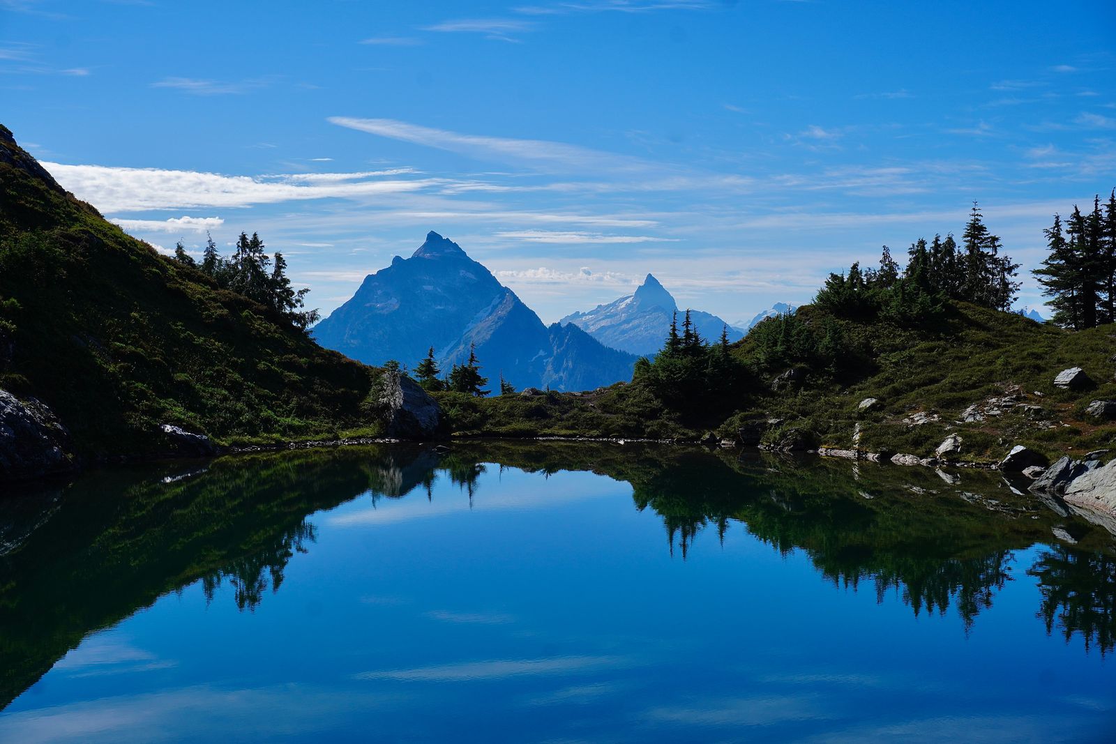 Trees reflected in a tarn below jagged peaks, Cascades