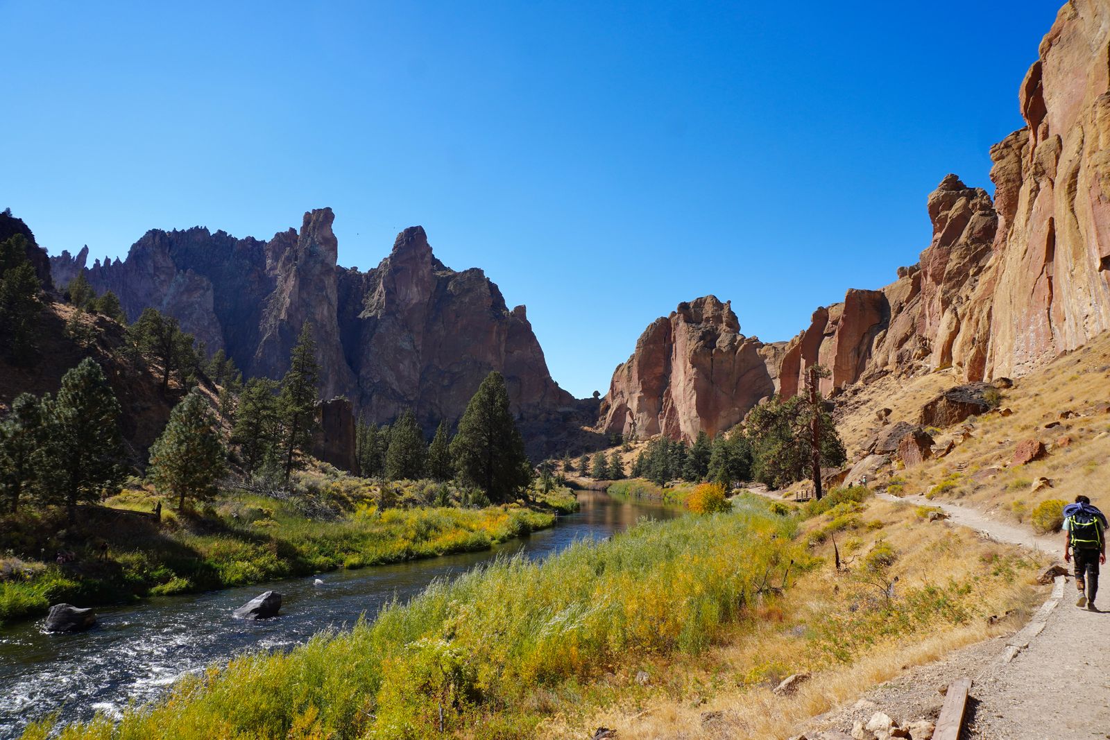 A hiker on a riverside trail below Smith Rock