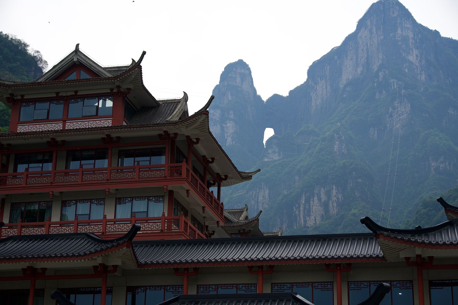 Rocky peaks with an arch above red tile-roofed buildings, Zhangjiajie