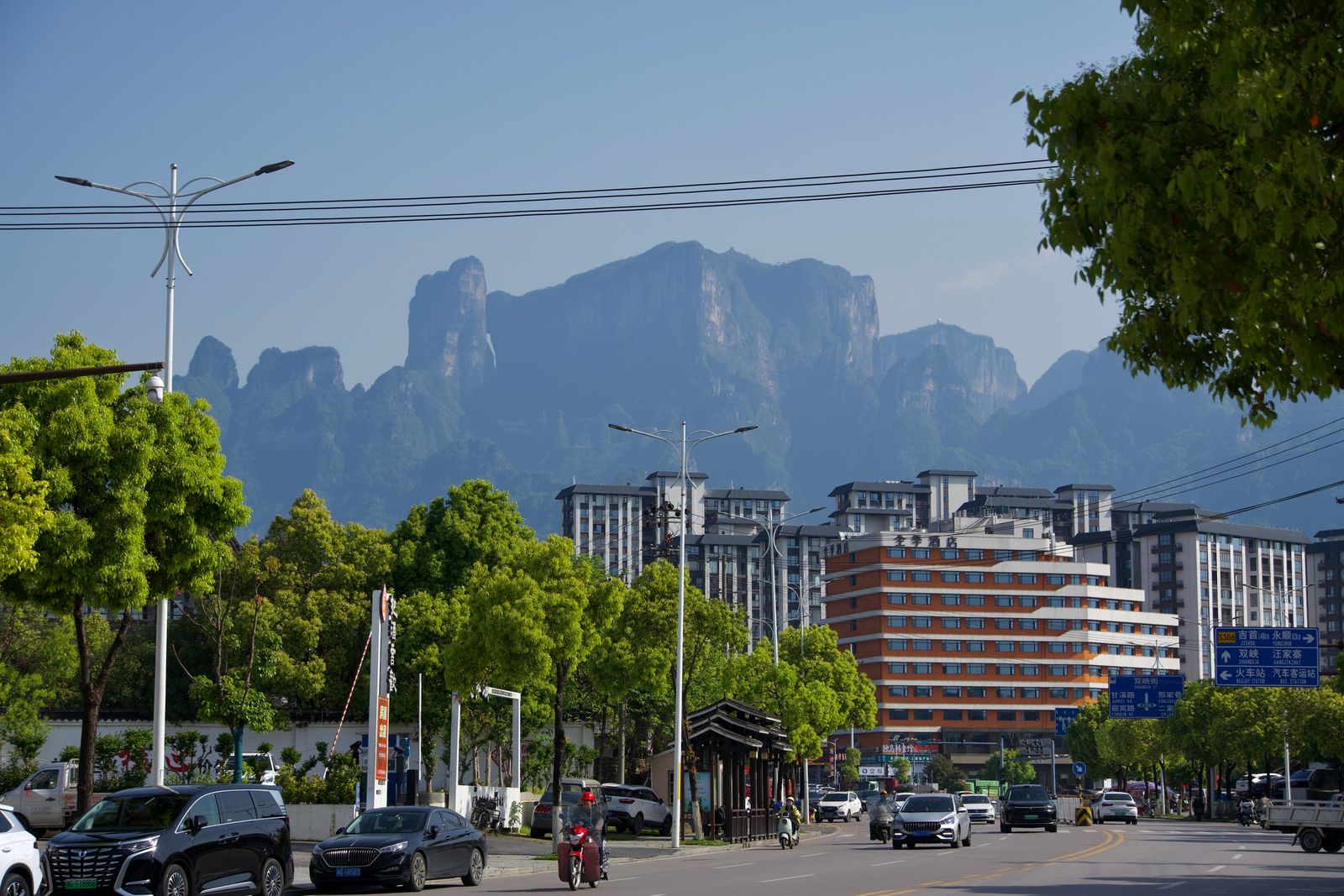Rocky peaks beyond buildings and a tree-lined street, Zhangjiajie